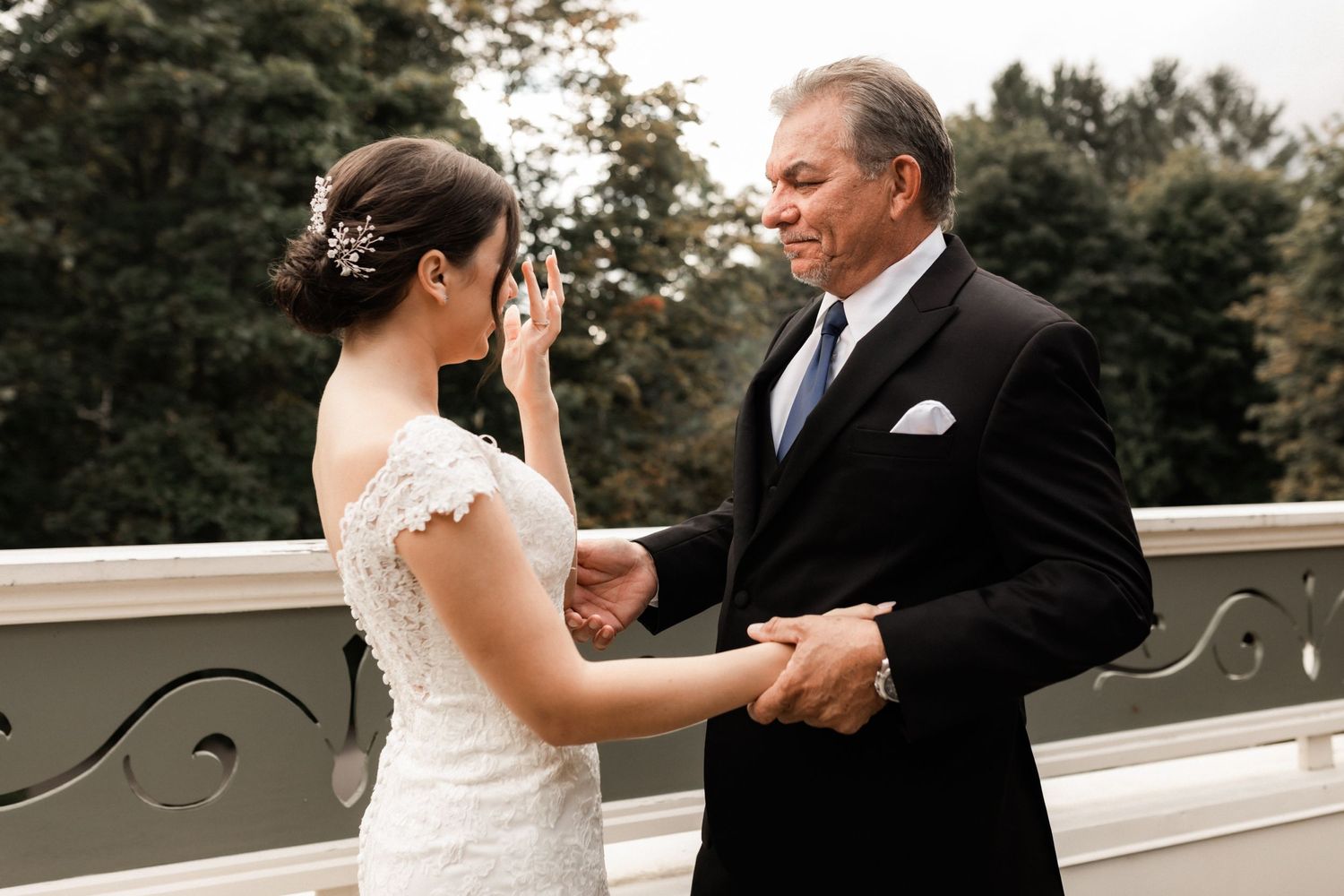 An emotional wedding moment captured on an elegant white balcony.