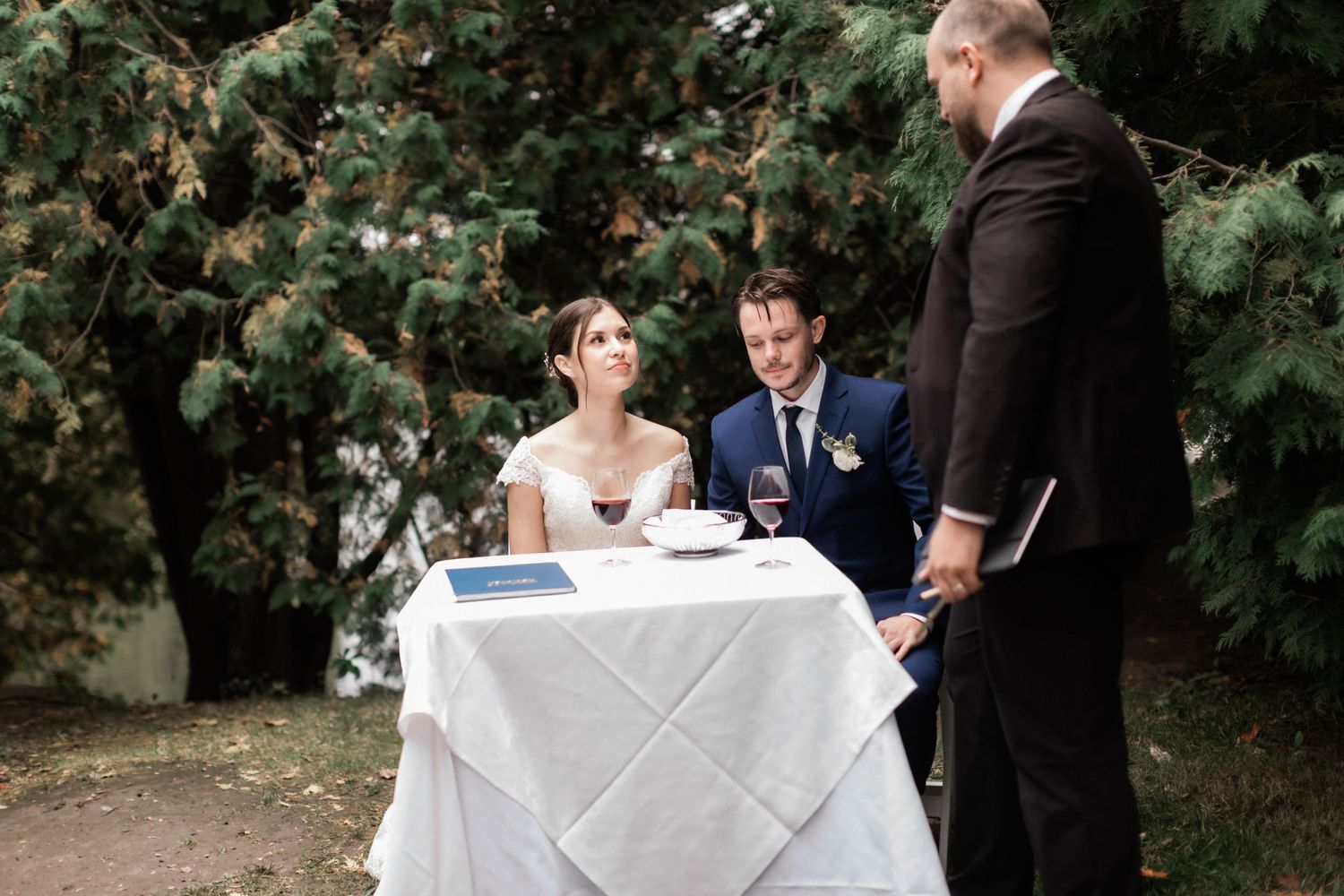 Garden wedding ceremony with flower girl watching couple exchange vows under natural arch.