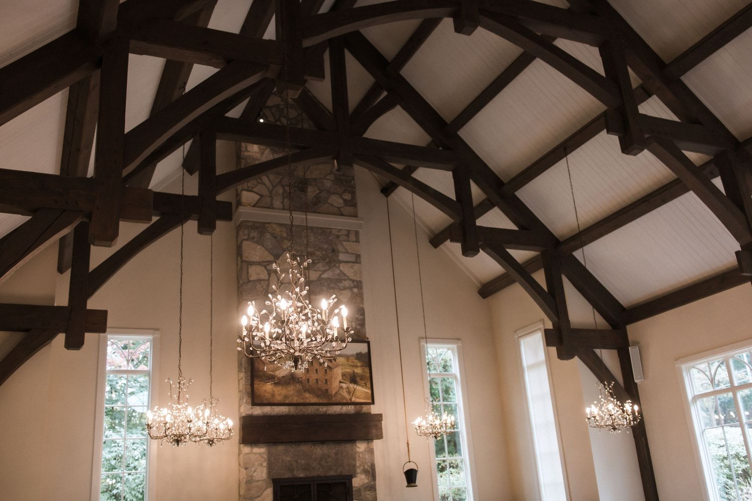 Elegant wedding venue interior with exposed wooden beam ceiling and crystal chandeliers.