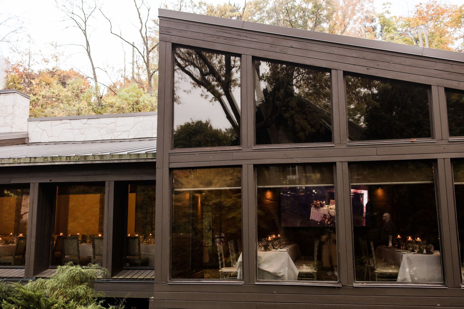 Modern wedding venue exterior with large glass windows and contemporary architecture at dusk.