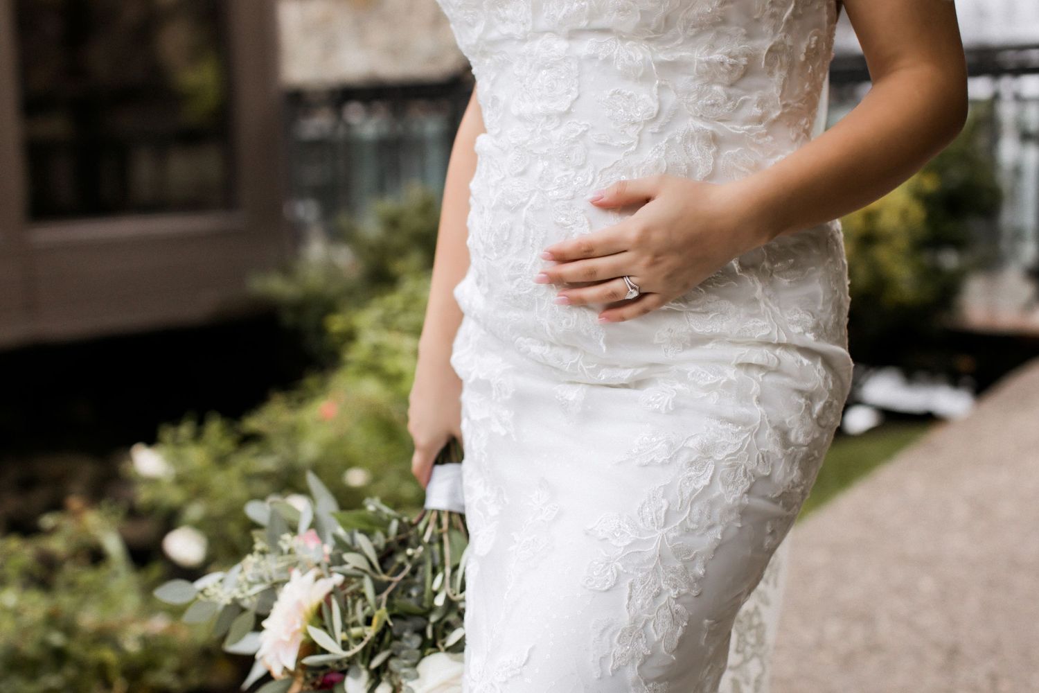 Detail shot of delicate lace wedding dress pattern and floral bouquet.