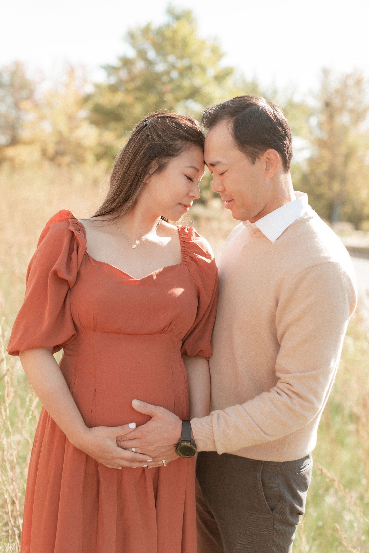 Intimate maternity portrait of couple touching foreheads in warm afternoon light.