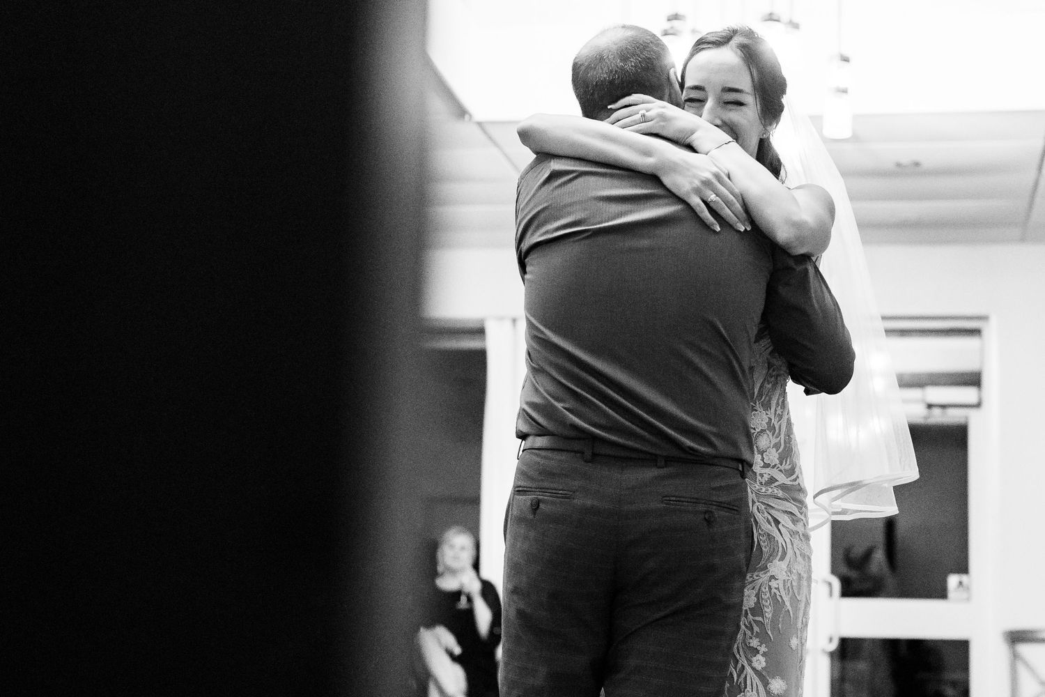A tender black and white photograph capturing an emotional embrace during a wedding celebration.