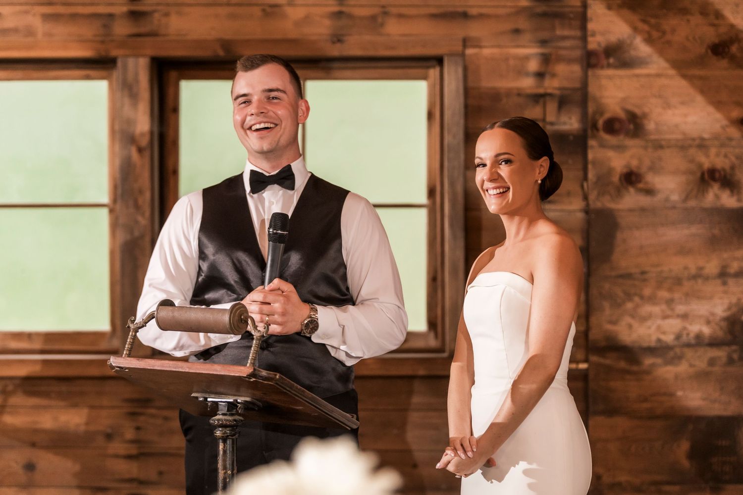 Wedding celebration moment captured in a rustic wood-paneled venue with elegant table settings.