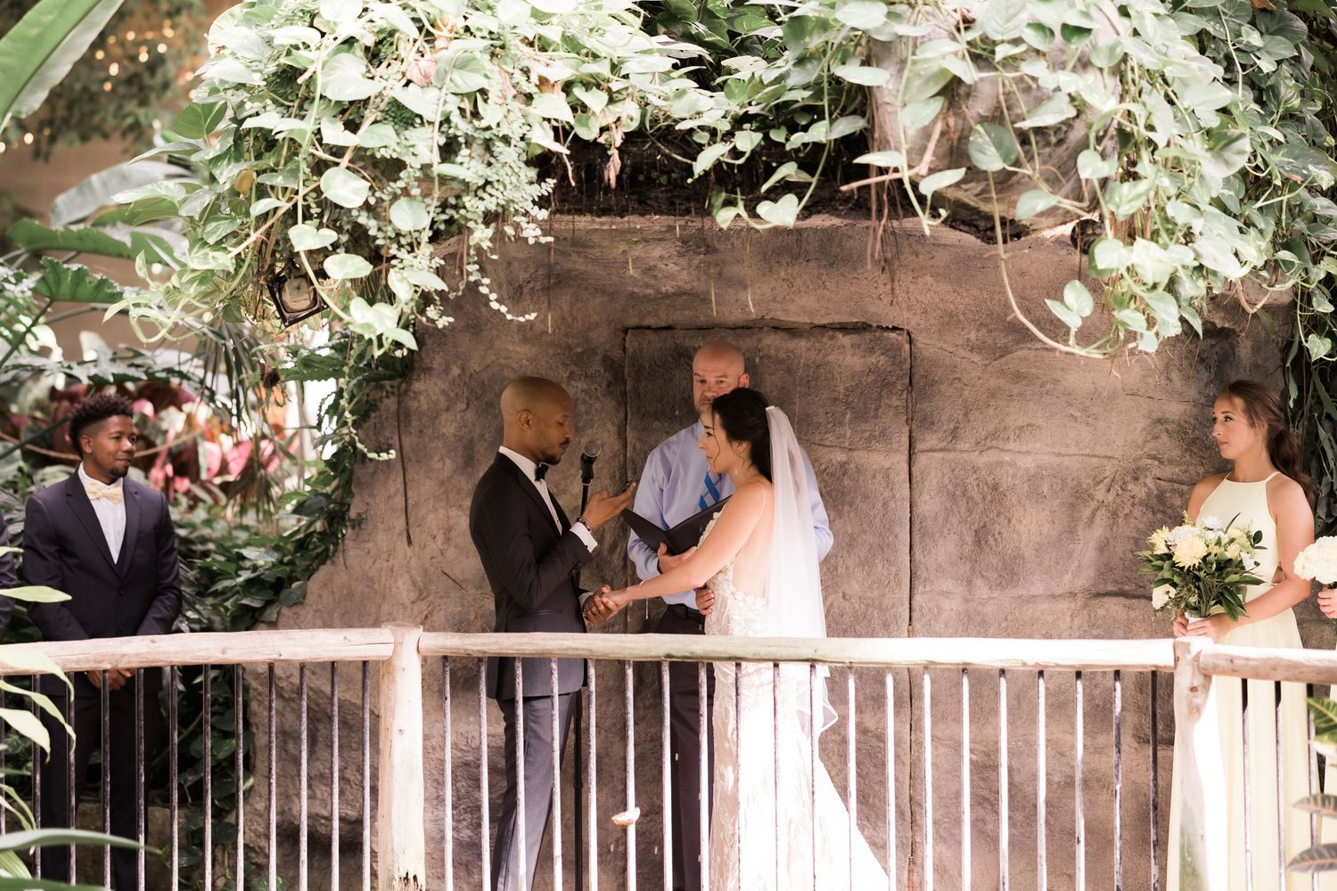 Wedding ceremony taking place on a rustic balcony decorated with cascading white flowers.