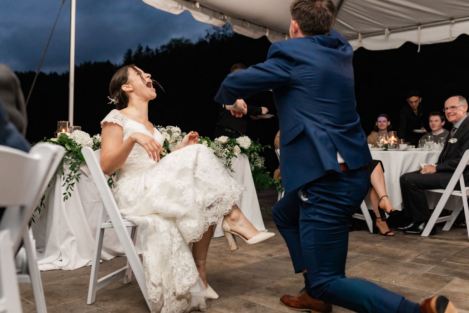 Lively dancing moment captured during an evening wedding reception under a tent.