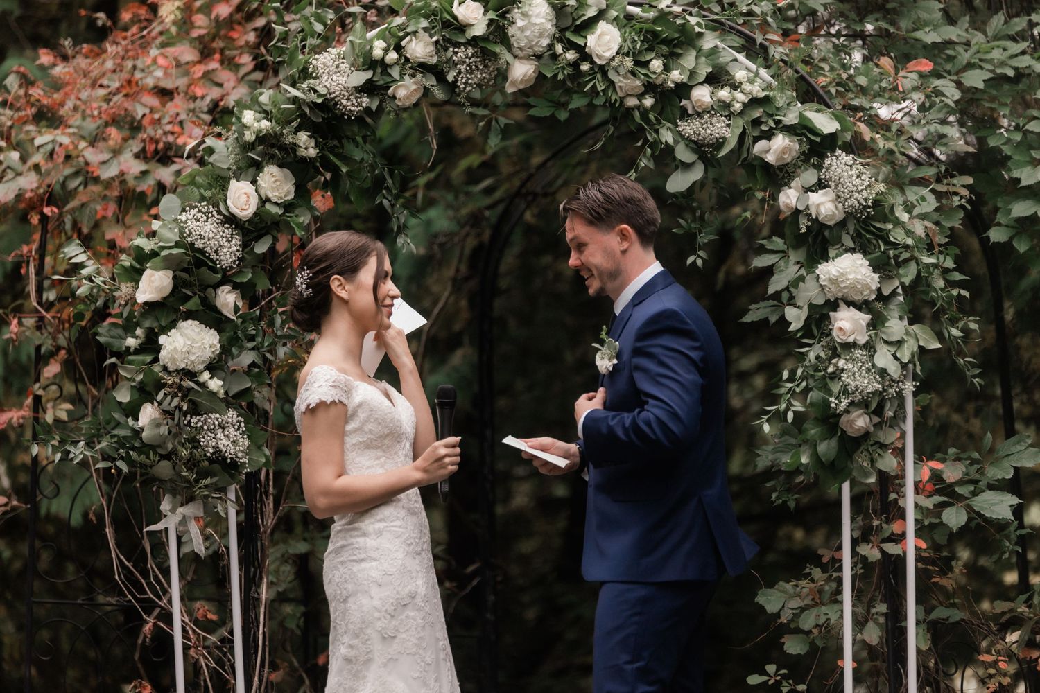 A couple exchanges vows beneath a floral arch during their garden wedding ceremony.