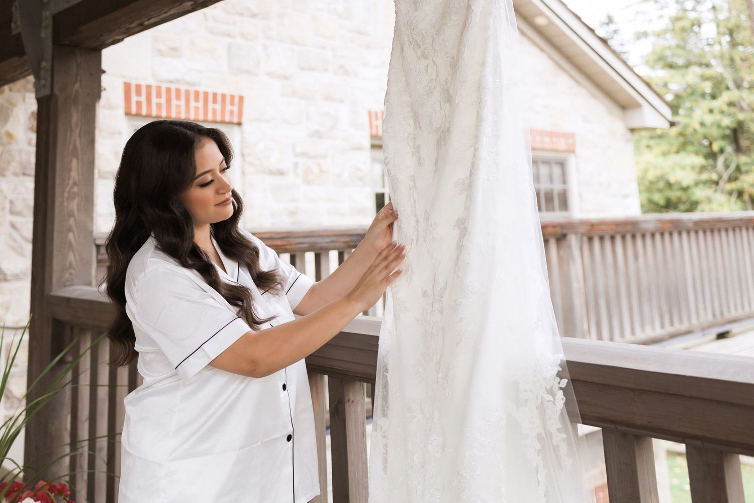 A person in white clothing examining a wedding dress on a covered porch.