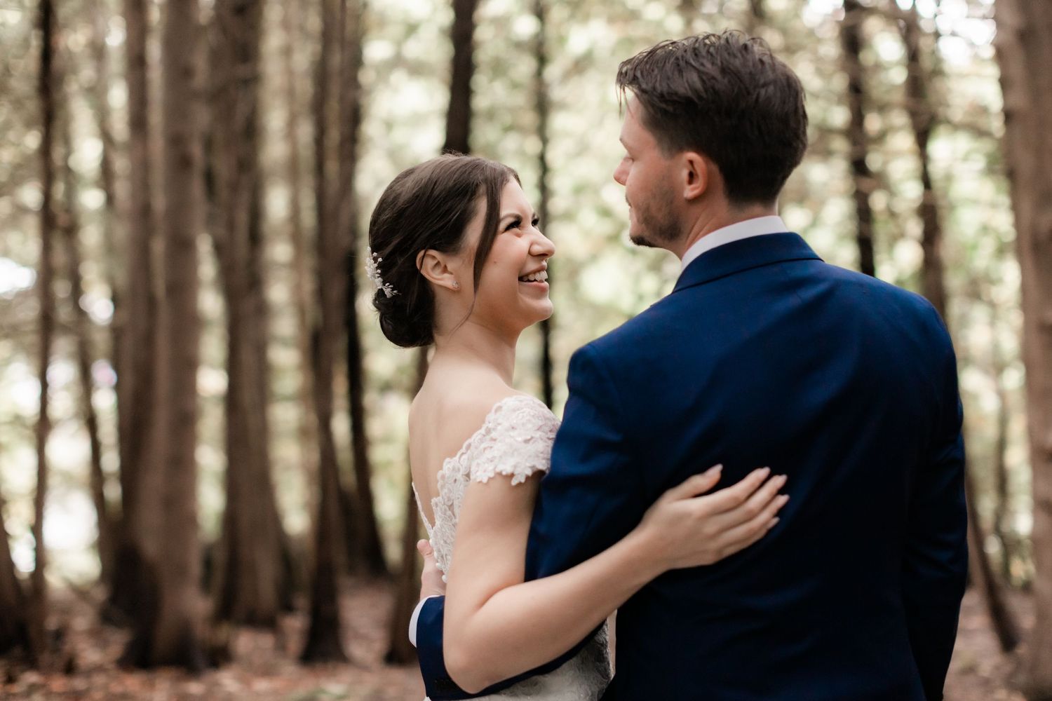 Joyful wedding moment captured between couple in a forest setting with natural light.