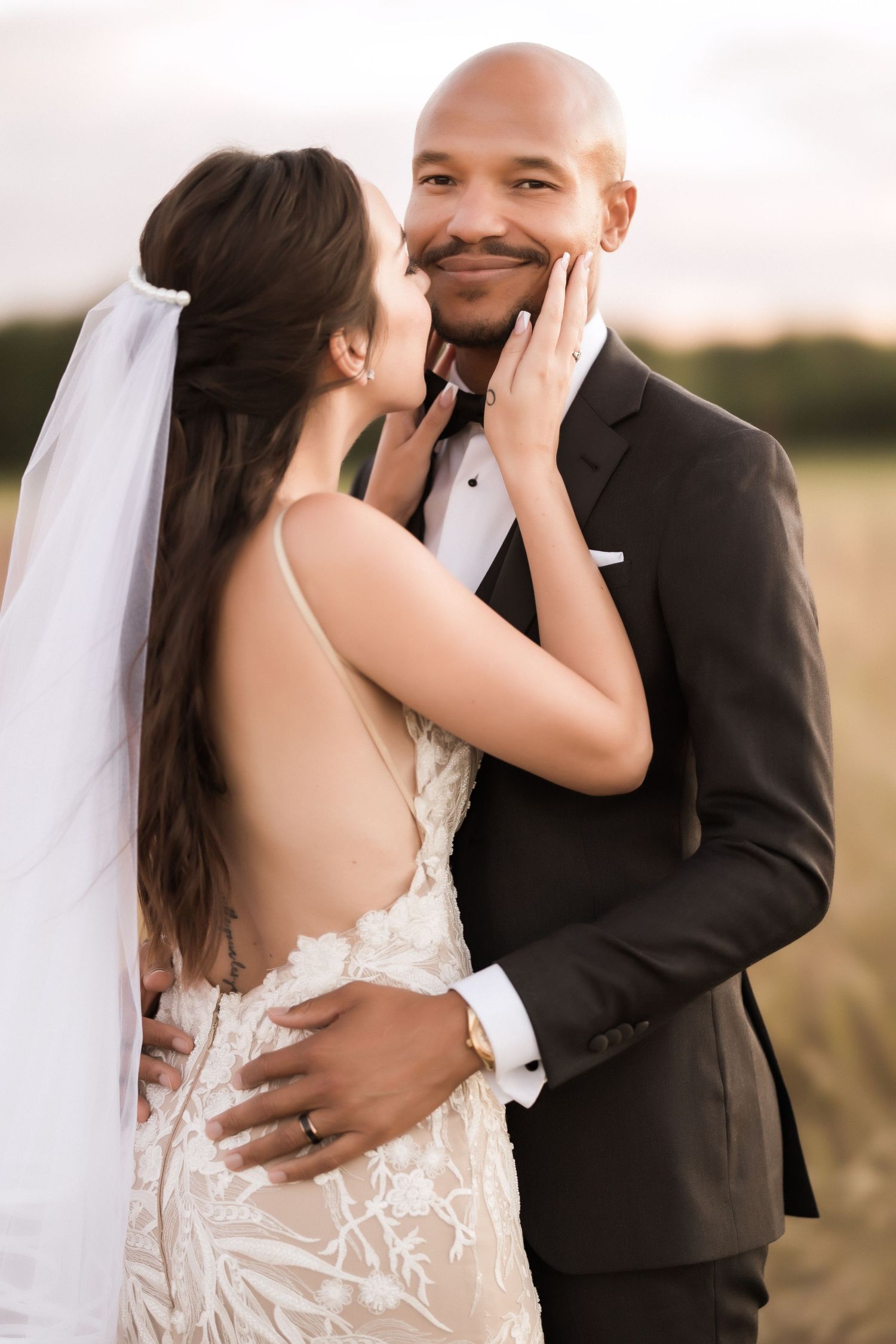 Intimate wedding portrait showing tender moment between couple in formal attire against natural backdrop.