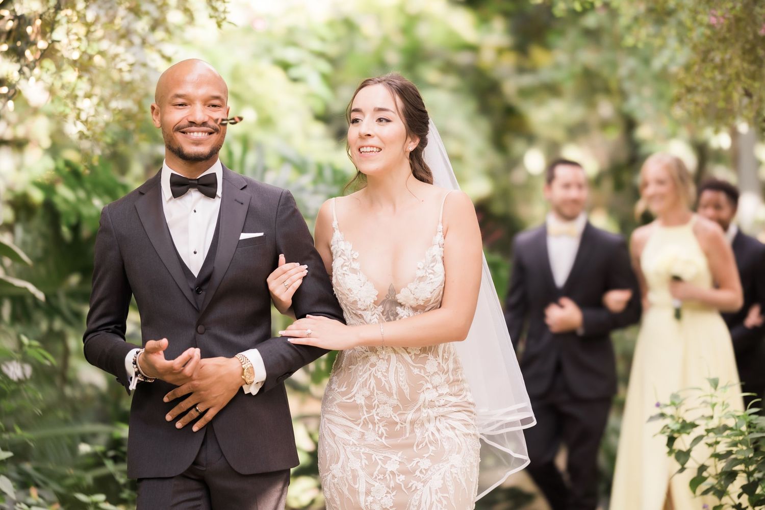 Happy couple celebrating during outdoor wedding ceremony with guests in background.