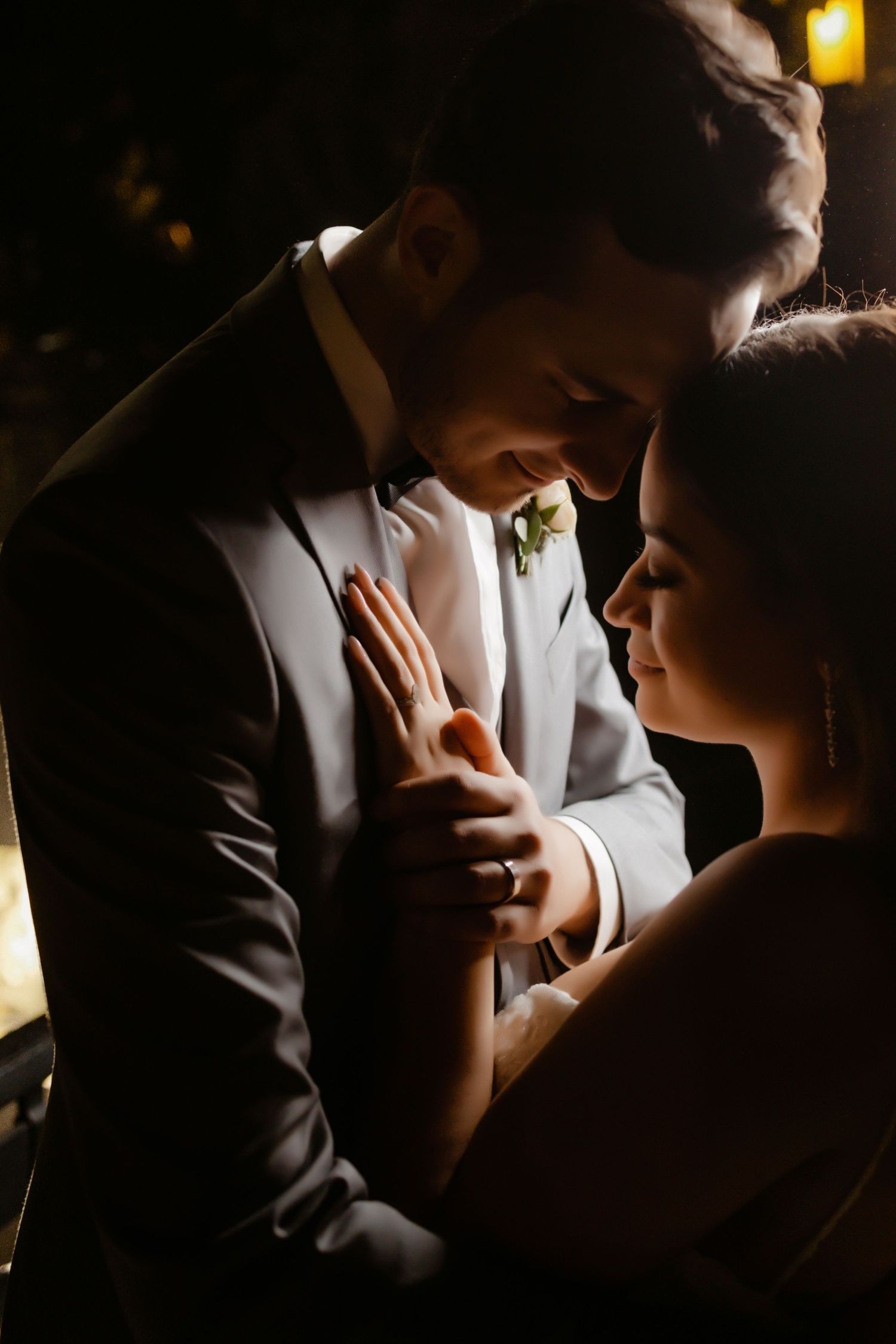 Dramatic backlit portrait of a couple in formal attire sharing an intimate moment.
