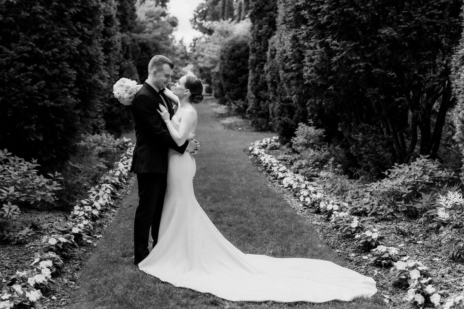 Black and white wedding photos captured in a scenic garden path setting.