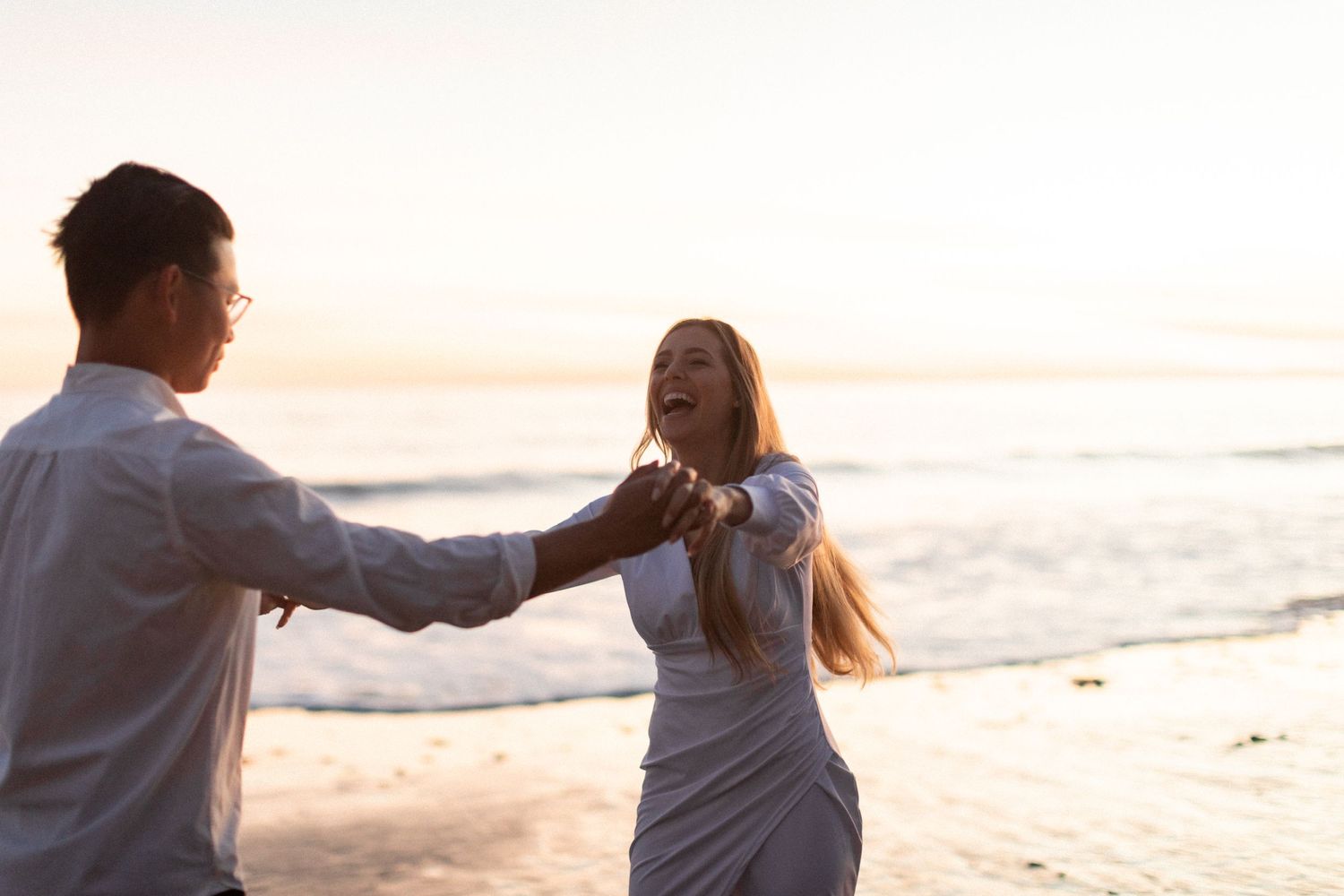 Couple dancing together on beach during sunset photoshoot.