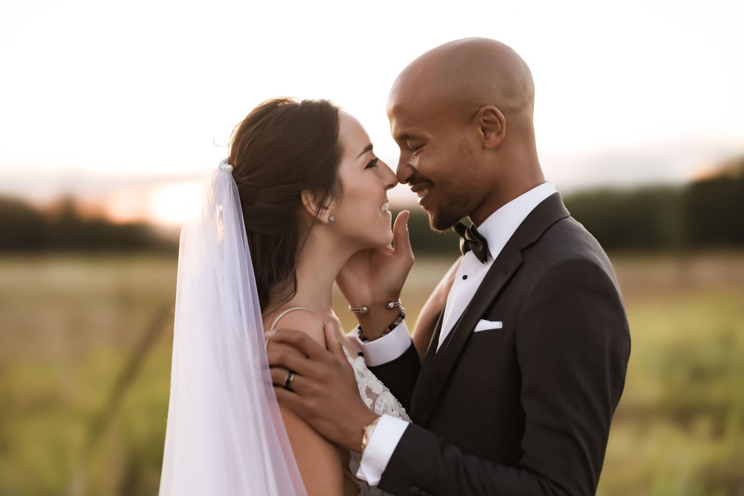 Tender moment between newlyweds captured in warm evening light during outdoor photo session.