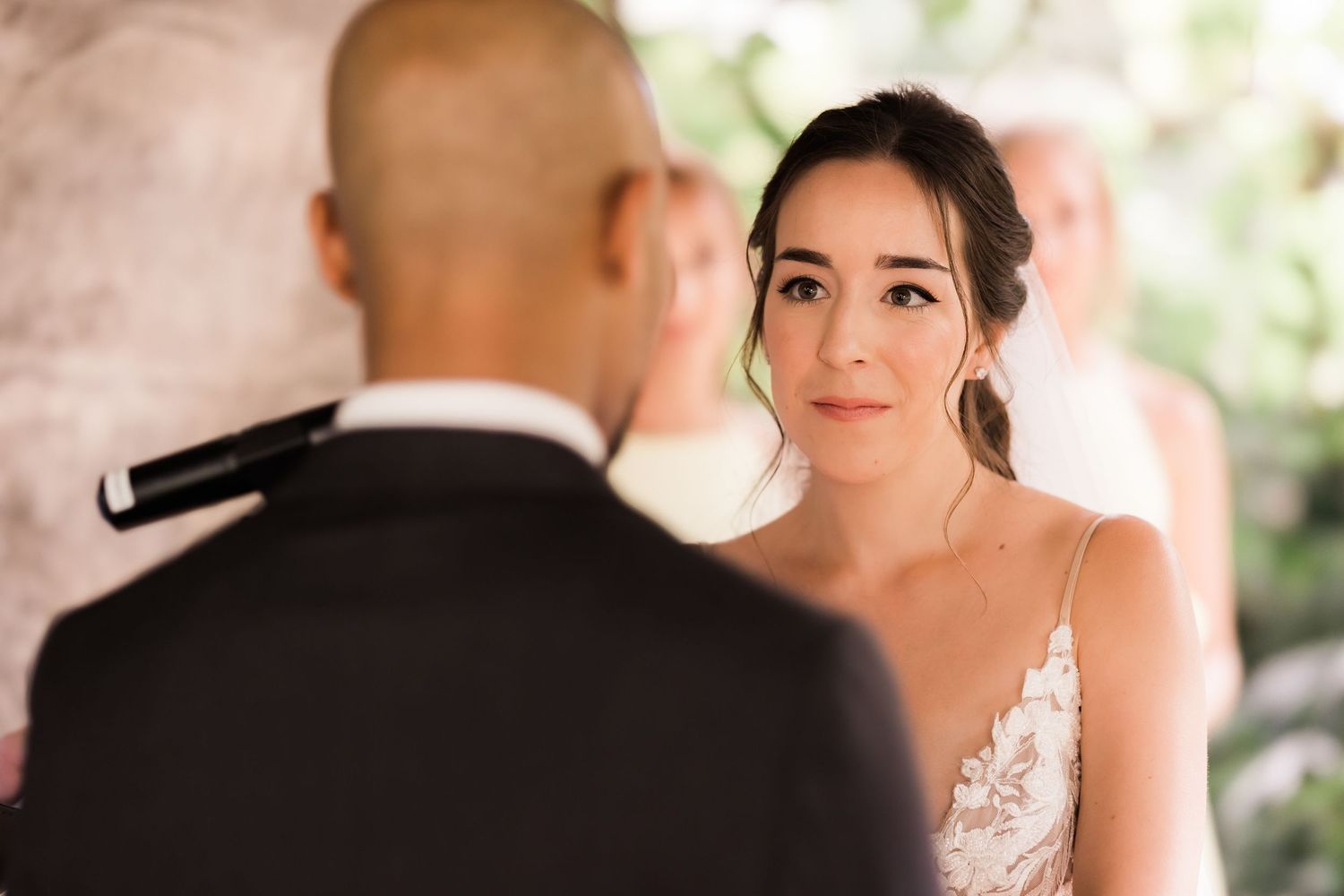 Close-up of bride in lace dress during intimate outdoor wedding ceremony.