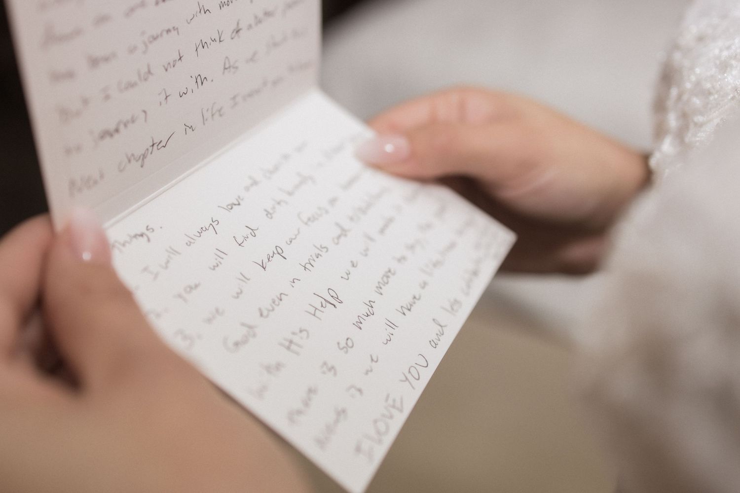 Close-up shot of hands holding handwritten letter with elegant cursive writing.