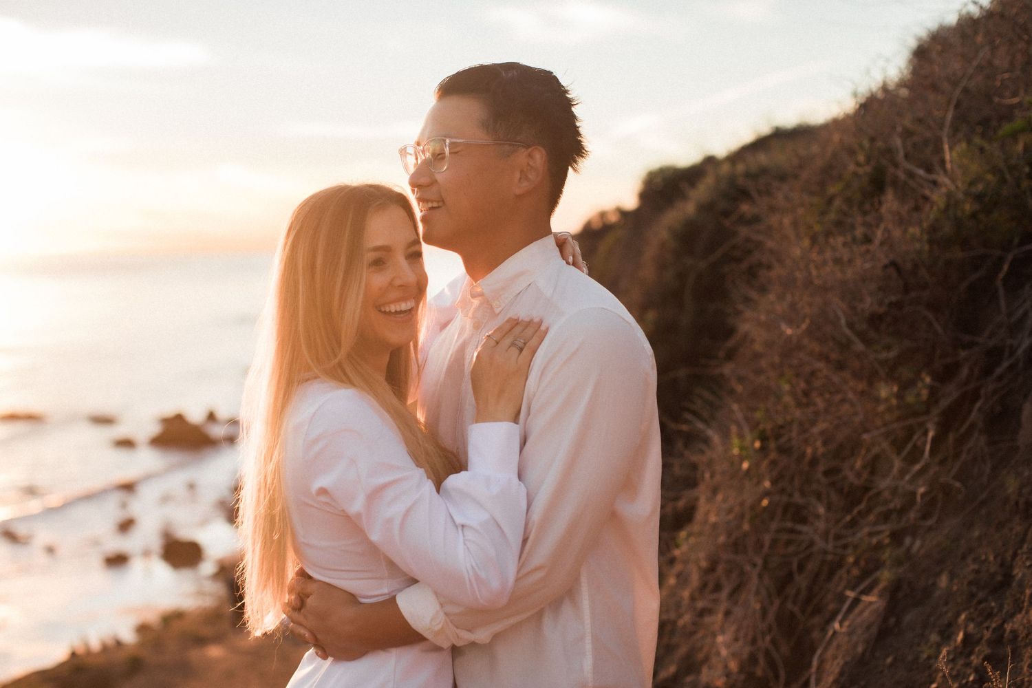 A romantic embrace captured during sunset on a California coastal cliff.