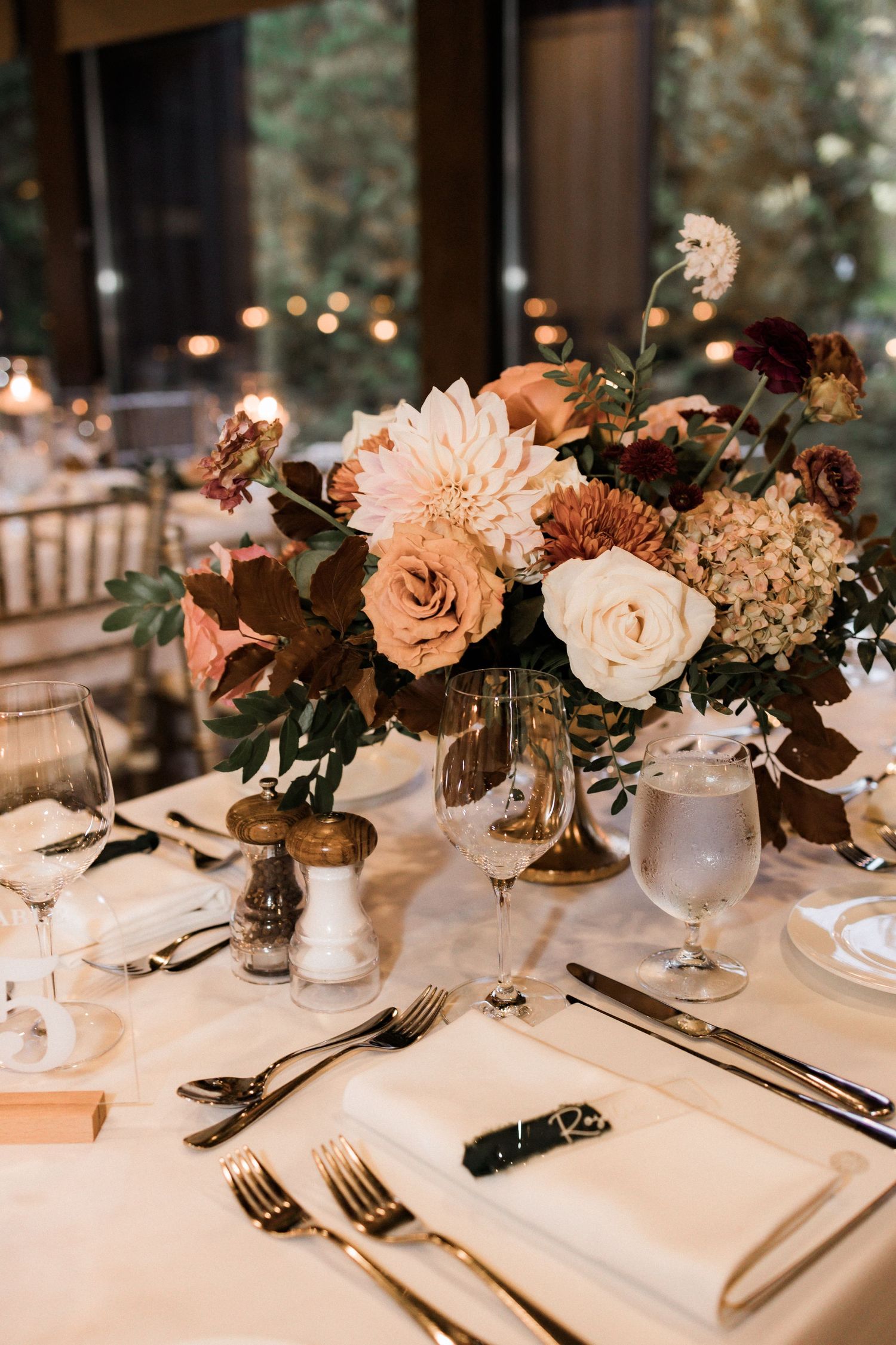 Close-up of a romantic table setting with blush floral centerpiece and formal place settings.