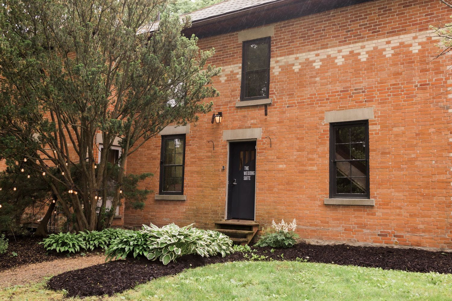 Seven landscape photos show red brick buildings with windows and mulched garden beds along their foundations.
