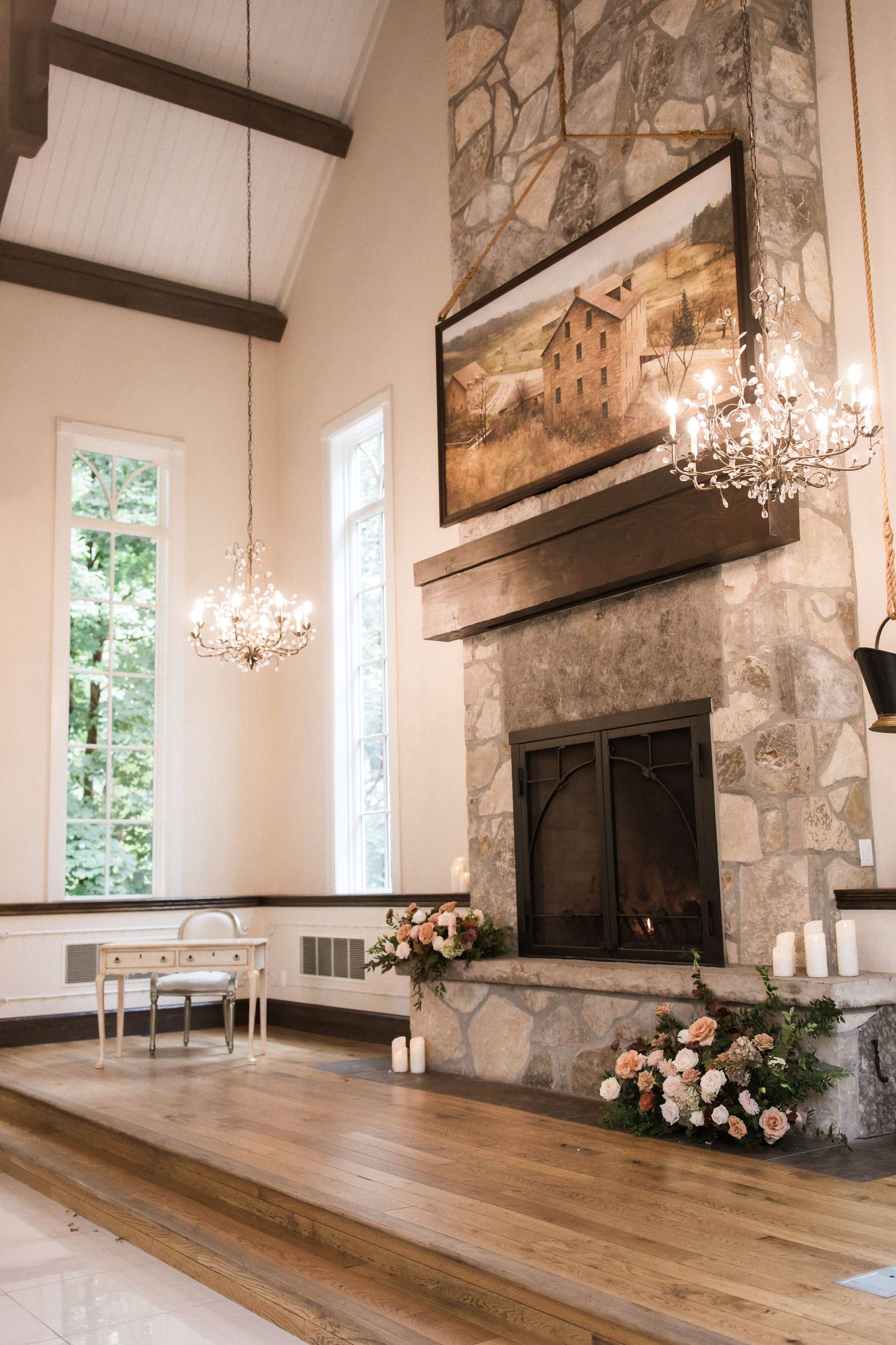 Wedding venue interior featuring stone fireplace, hardwood floors, and crystal chandeliers.