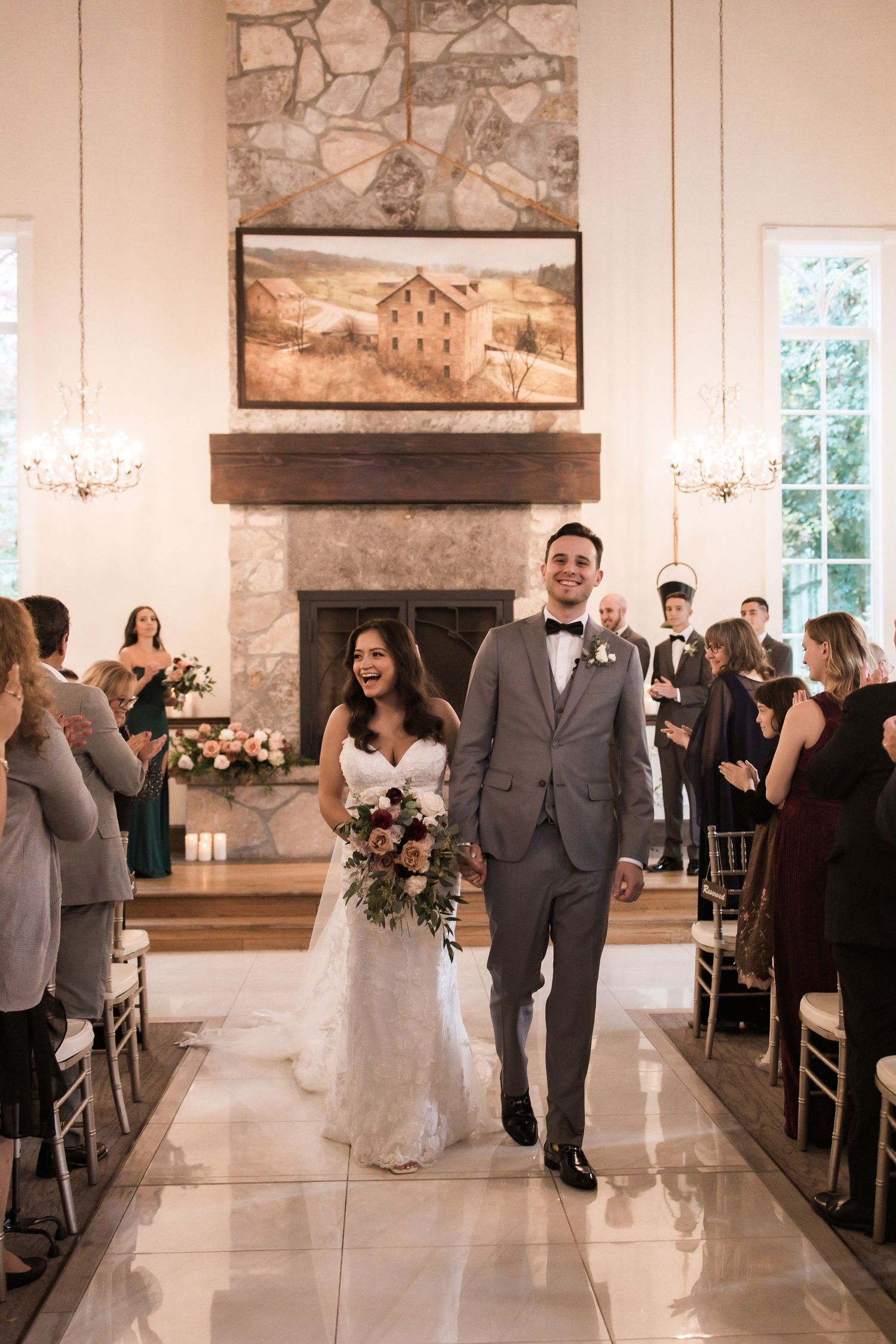 Wedding celebration in modern venue with rustic stone fireplace and desert landscape artwork.