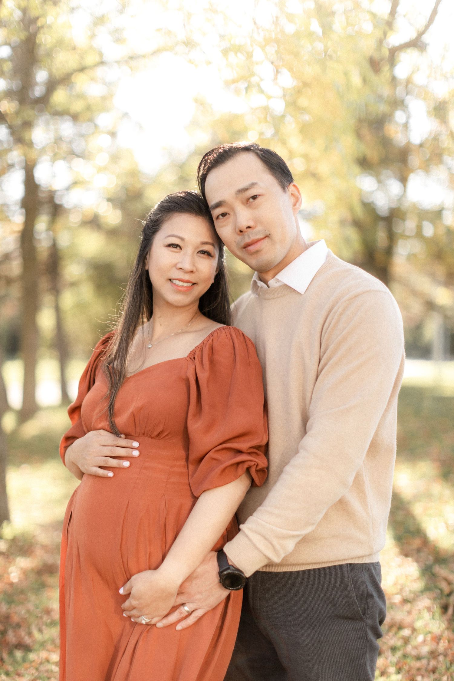 Expecting couple shares loving moment in golden autumn forest setting.