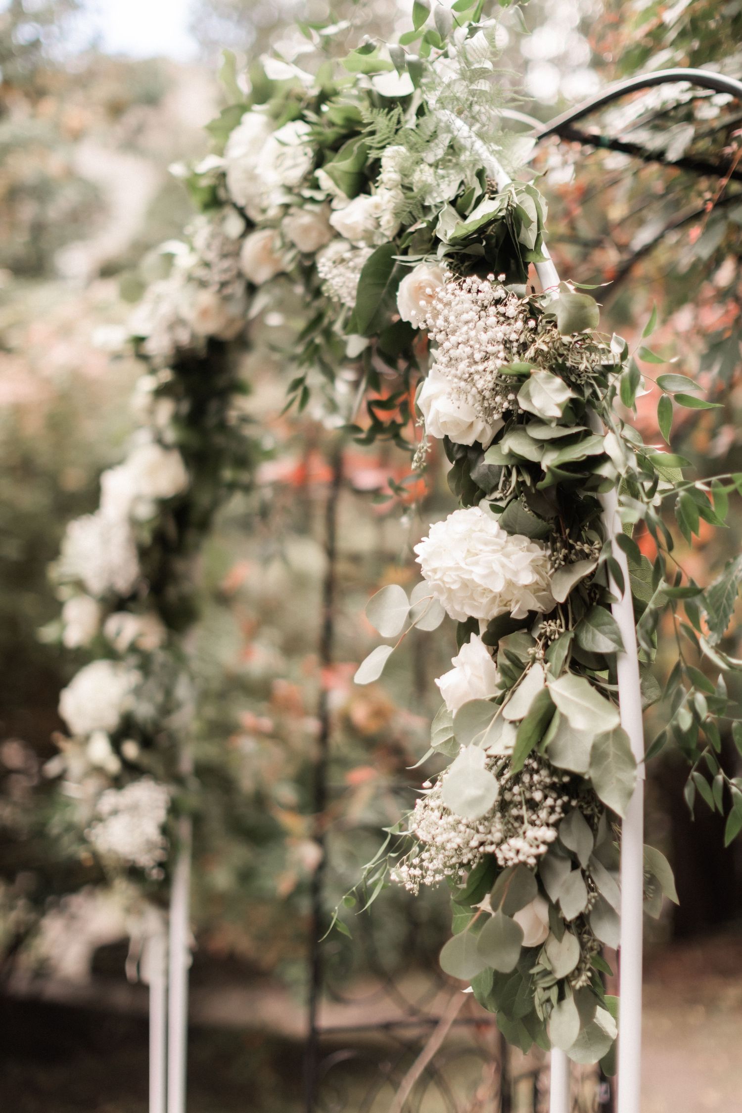 Elegant white floral and greenery wedding arch detail with delicate baby's breath and eucalyptus.