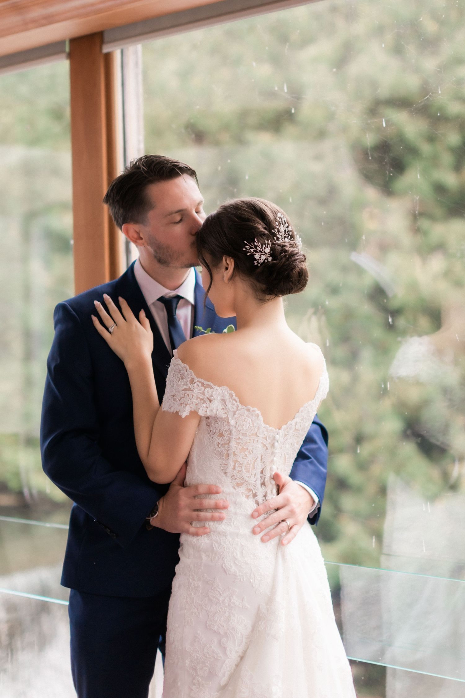 Intimate moment between newlyweds sharing an embrace by glass windows.