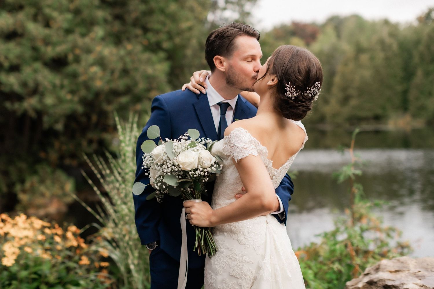 A romantic wedding portrait with couple embracing by a lake.