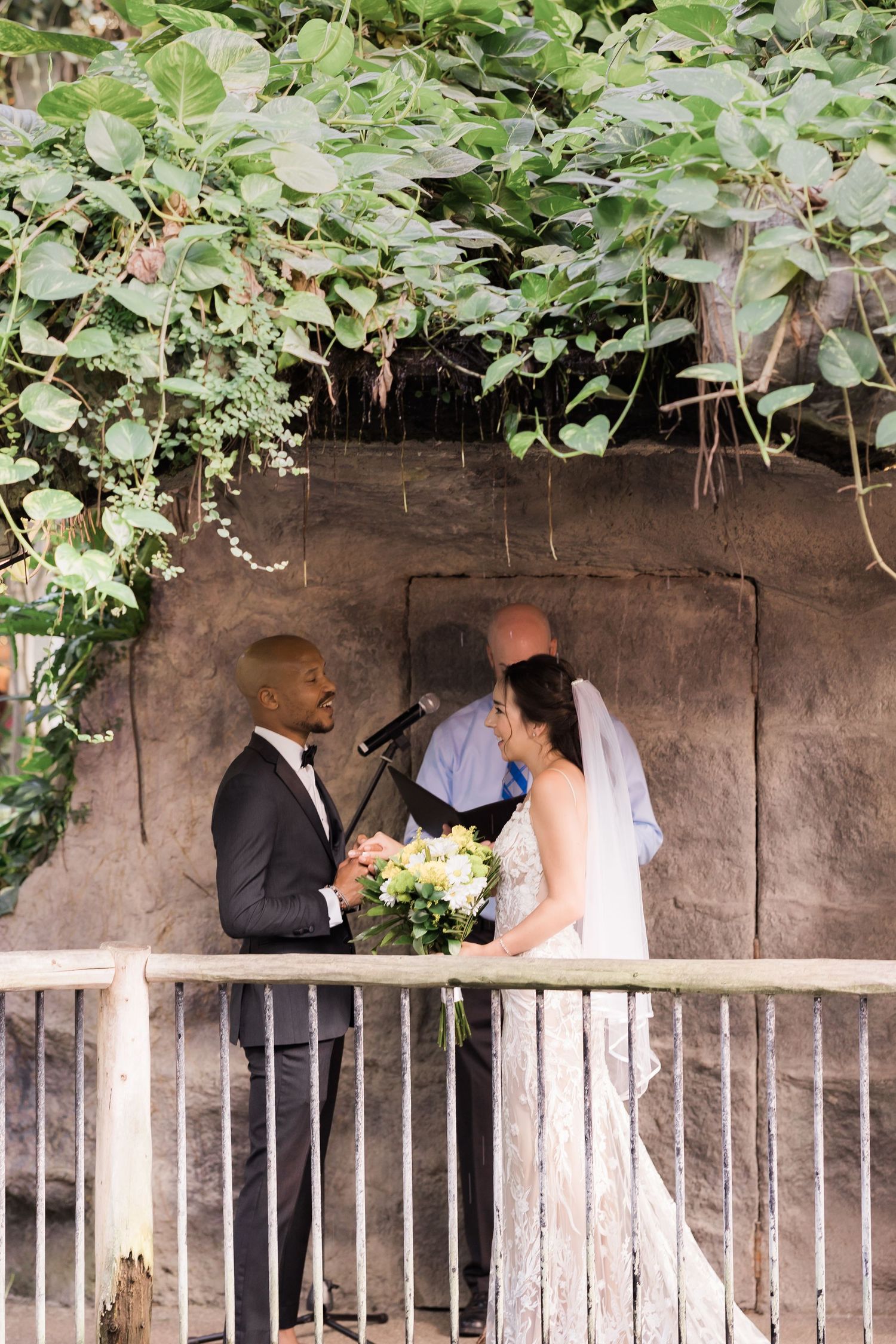 Couple exchanges vows on a rustic balcony surrounded by climbing vines.