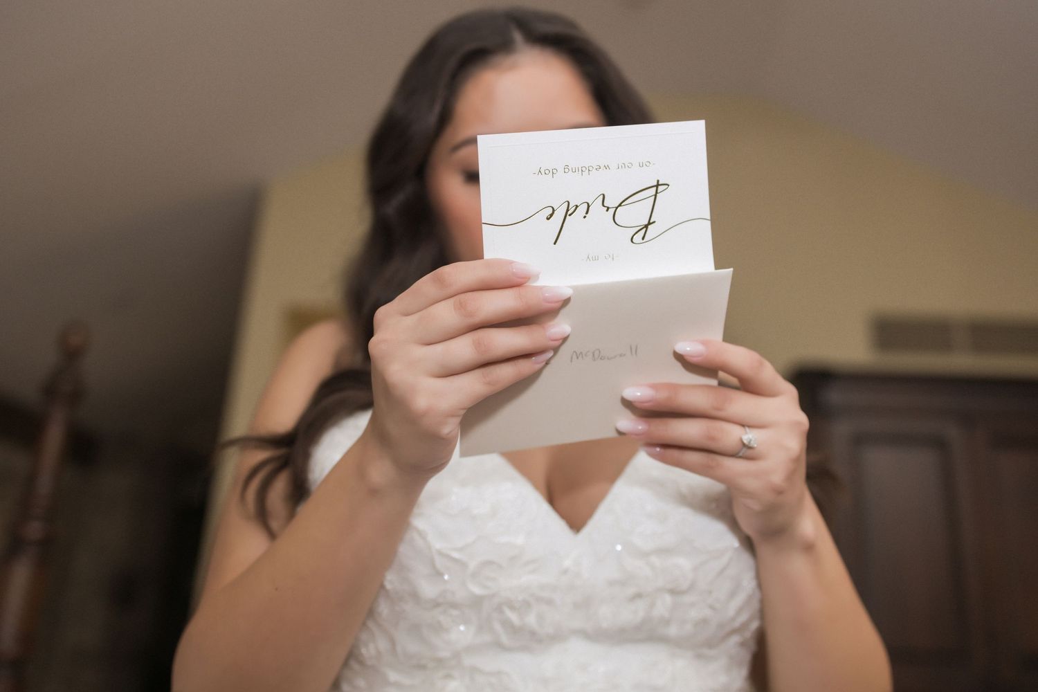 Bride in white dress reading a heartfelt letter on her wedding day.