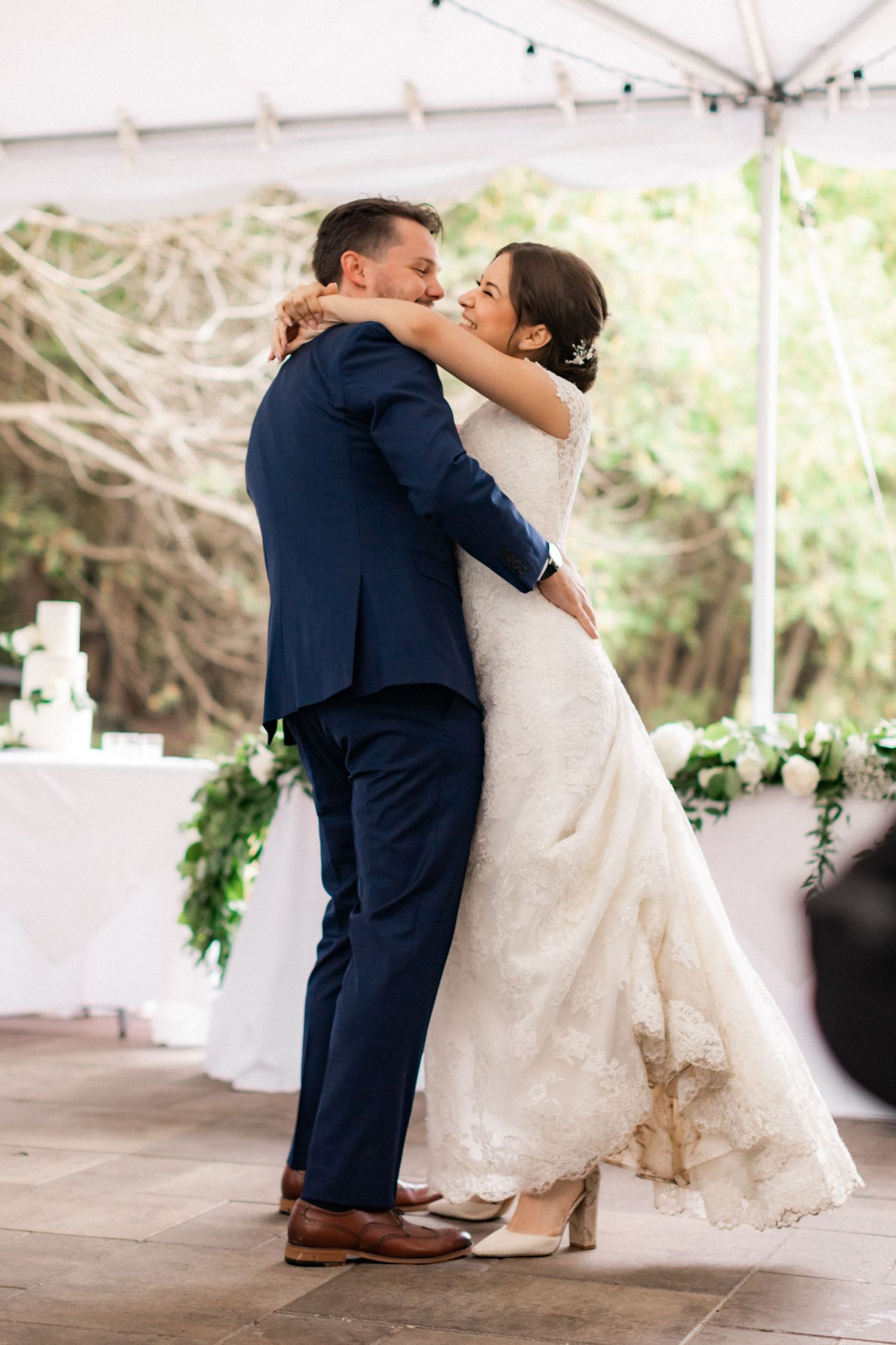 Couple shares their first dance under white tent at outdoor wedding reception.