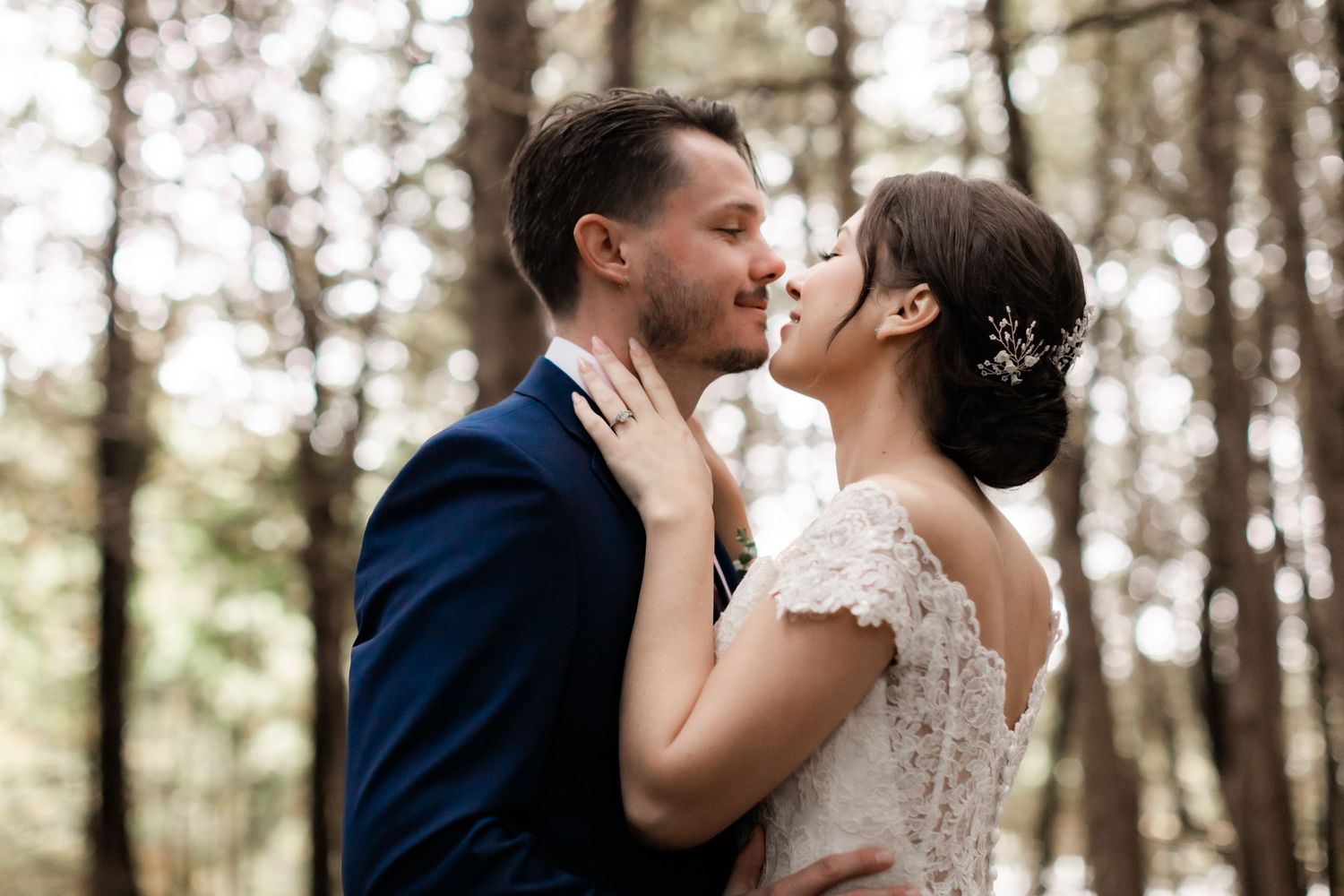 Tender wedding moment captured in forest with soft natural lighting and romantic atmosphere.