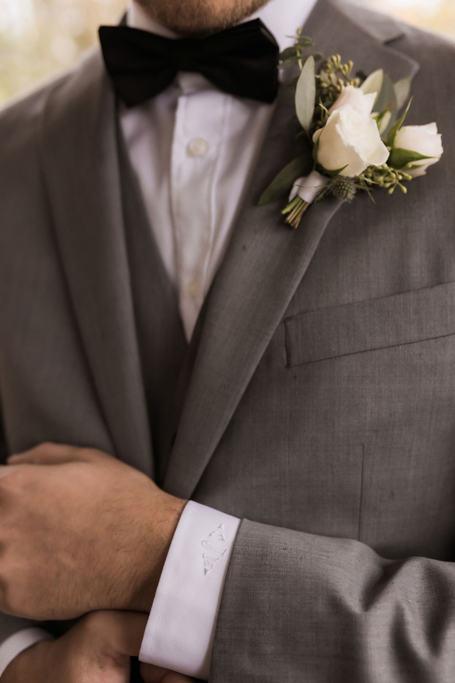 Close-up of gray suit with black bow tie and white rose boutonniere.