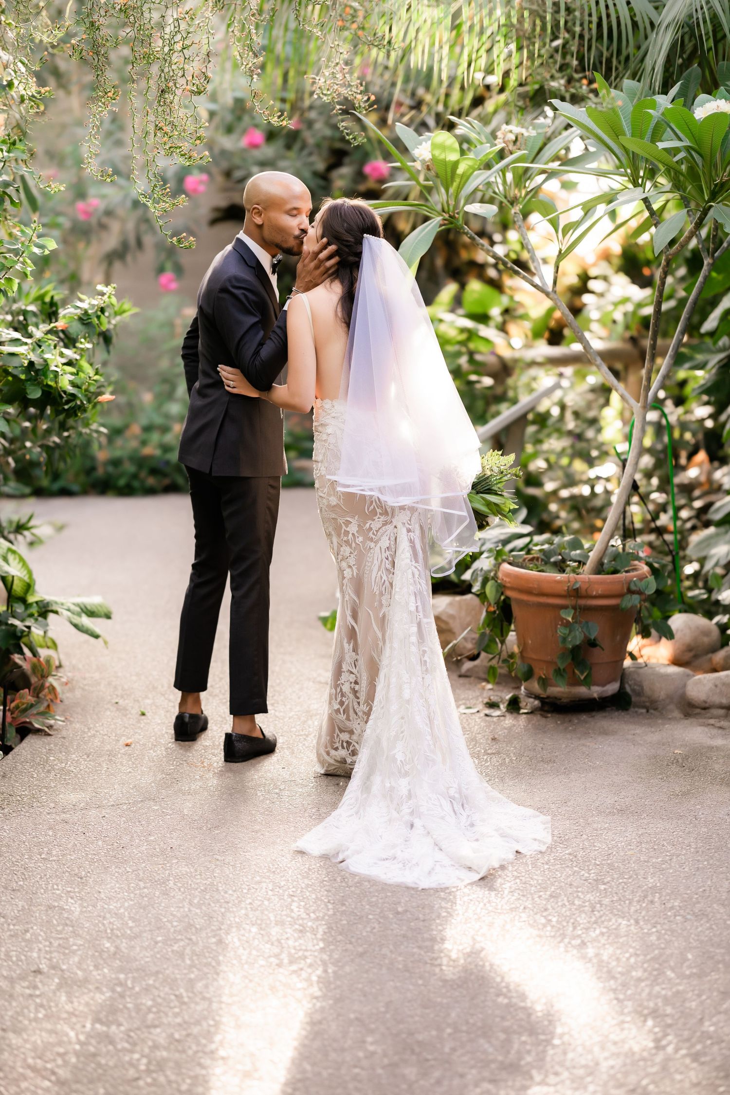 An intimate wedding moment captured between a couple in a lush botanical garden.