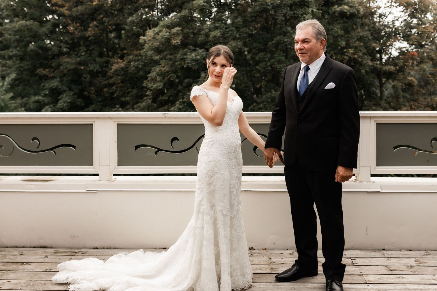 Candid wedding moment captured on white outdoor terrace with ornate details.