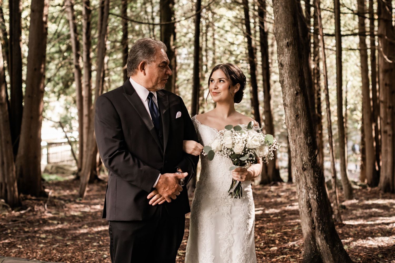 Candid moment between couple during outdoor garden wedding ceremony with floral backdrop.