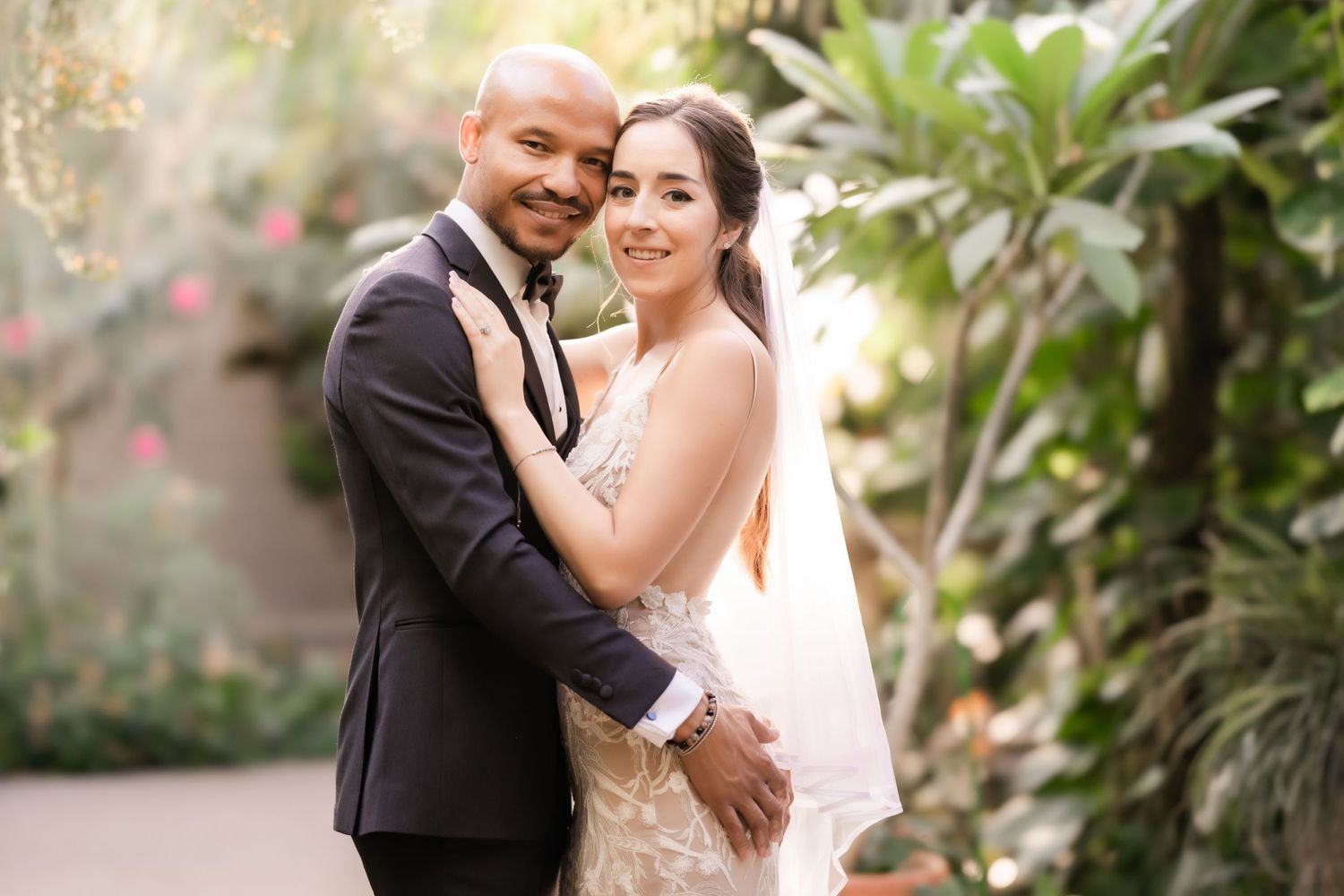 A joyful wedding portrait captured in a botanical garden setting.