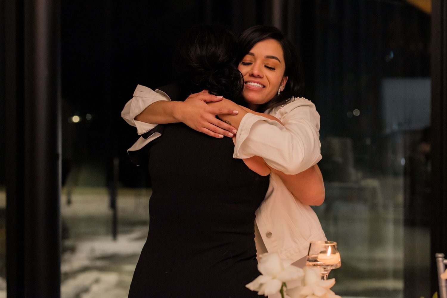 A heartfelt embrace shared during a wedding celebration in warm lighting.