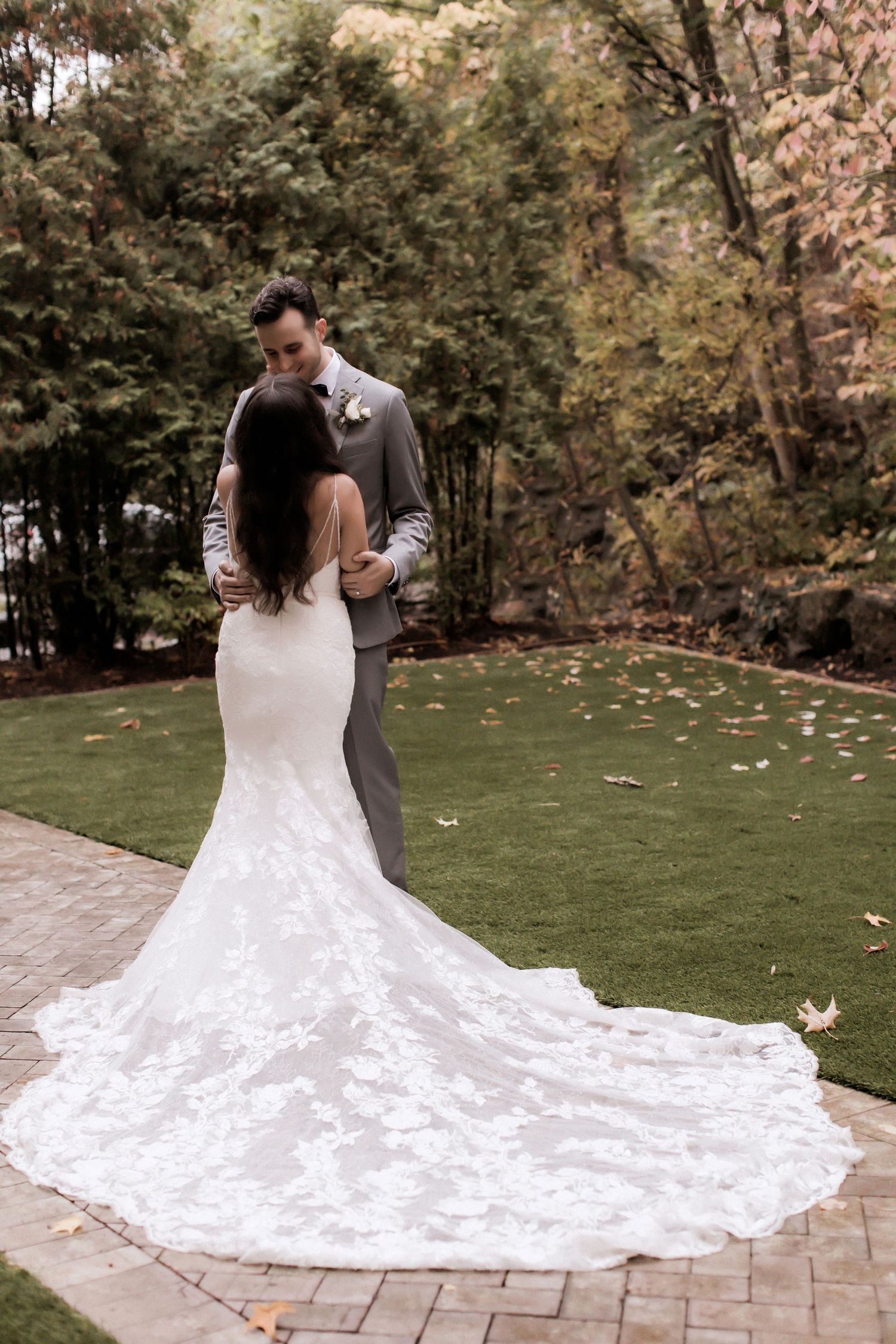 Romantic garden wedding portrait featuring bride's dramatic lace train on stone patio.