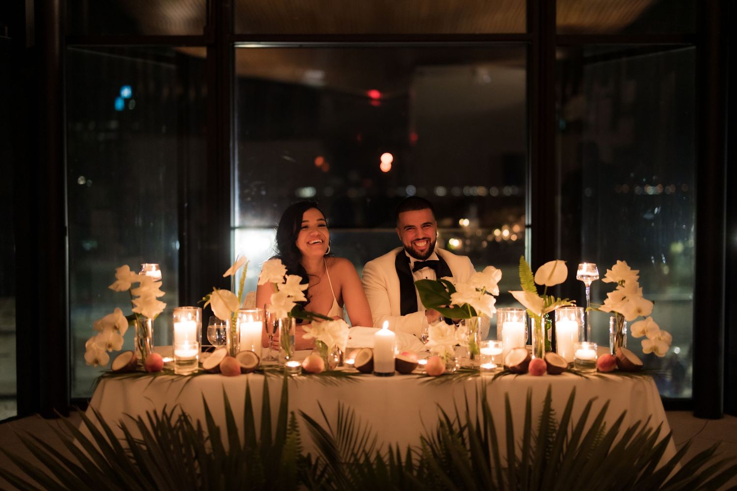 Wedding couple enjoys intimate candlelit dinner with decorative table settings at night.
