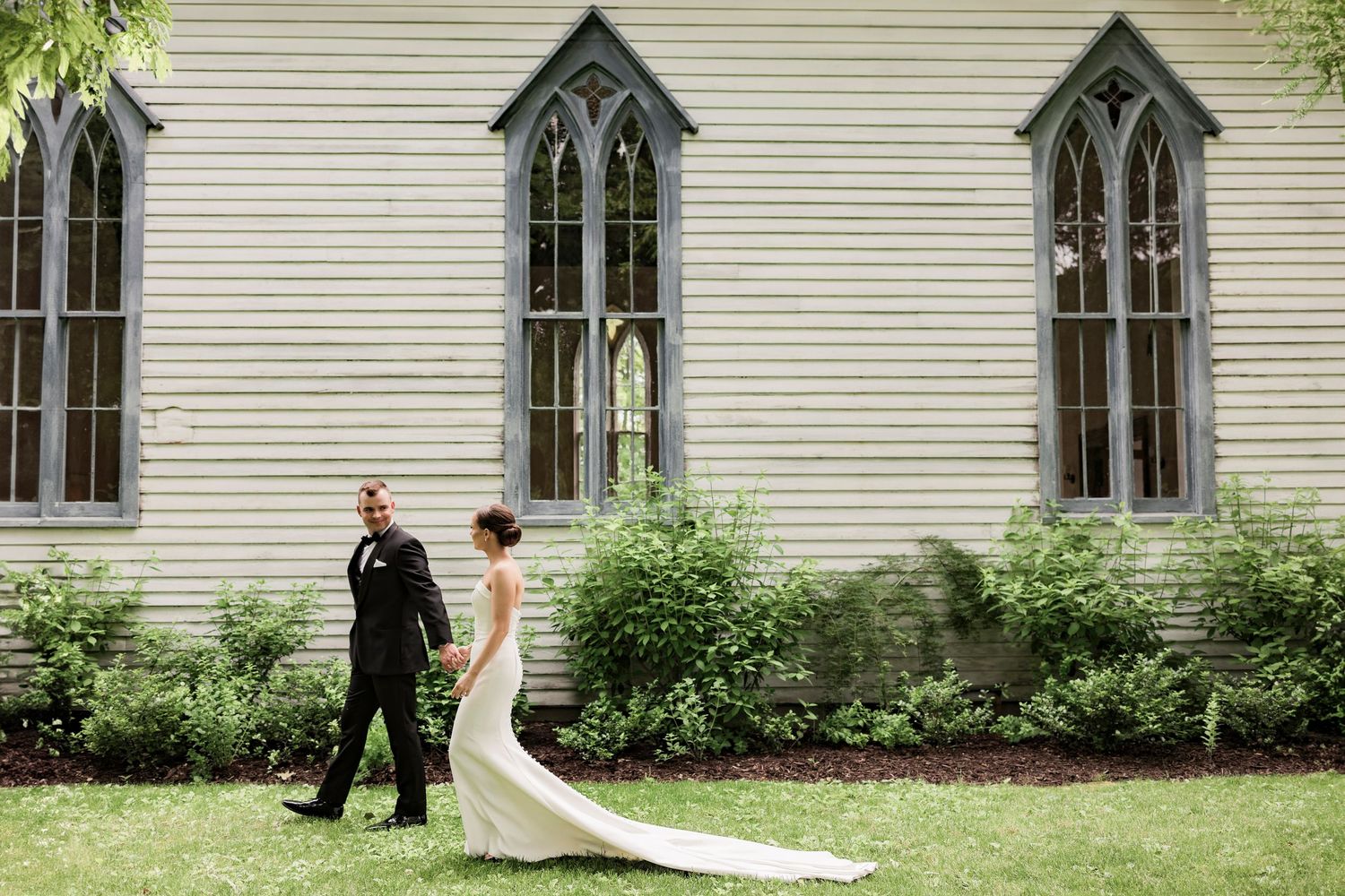 A historic white chapel with Gothic windows provides an elegant backdrop for wedding photography.