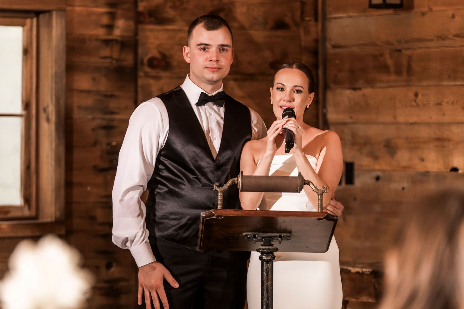 Formal reception event in a rustic barn venue with elegant table settings and window lighting.