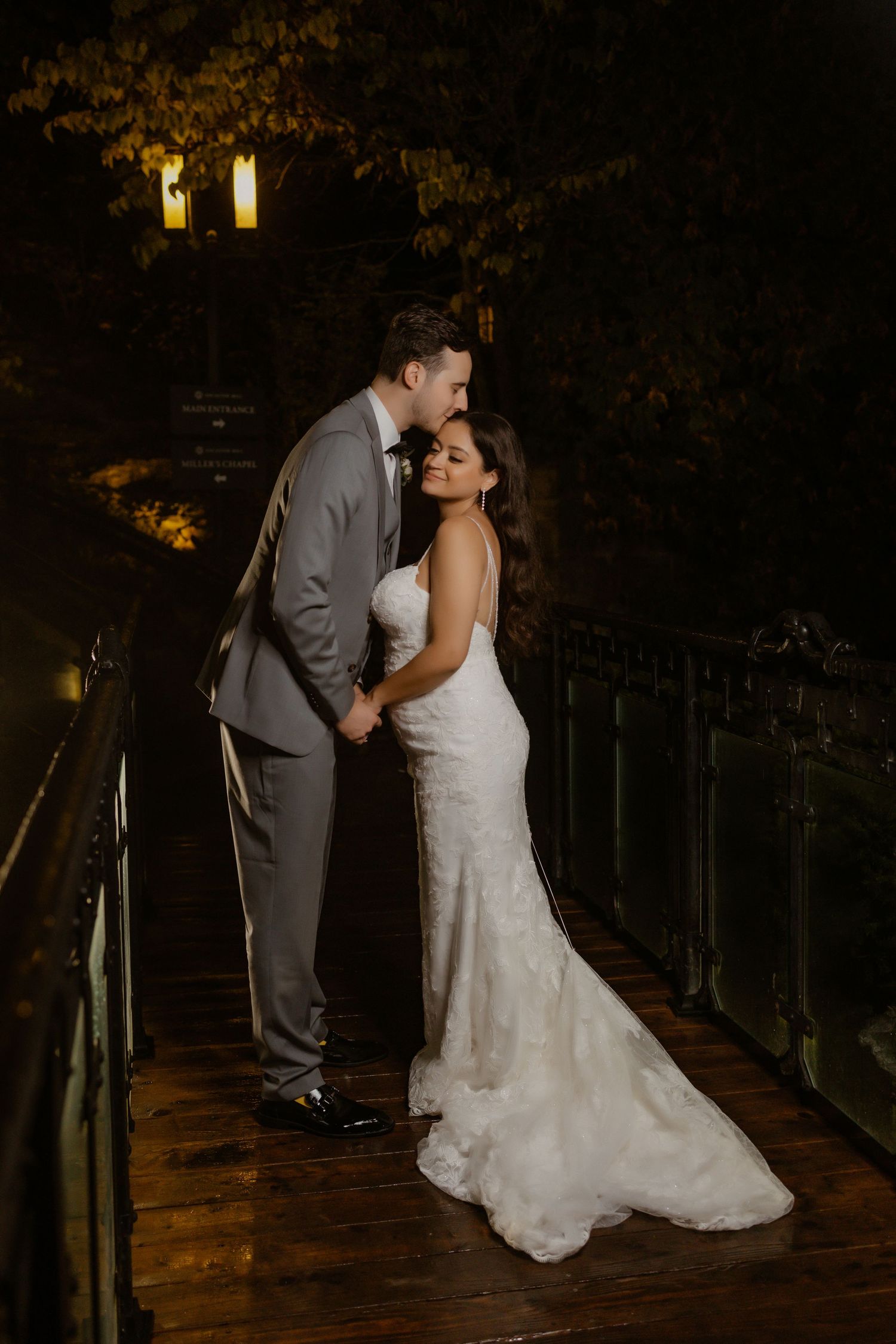Romantic nighttime portrait of newlyweds on a wooden deck with ambient lighting.