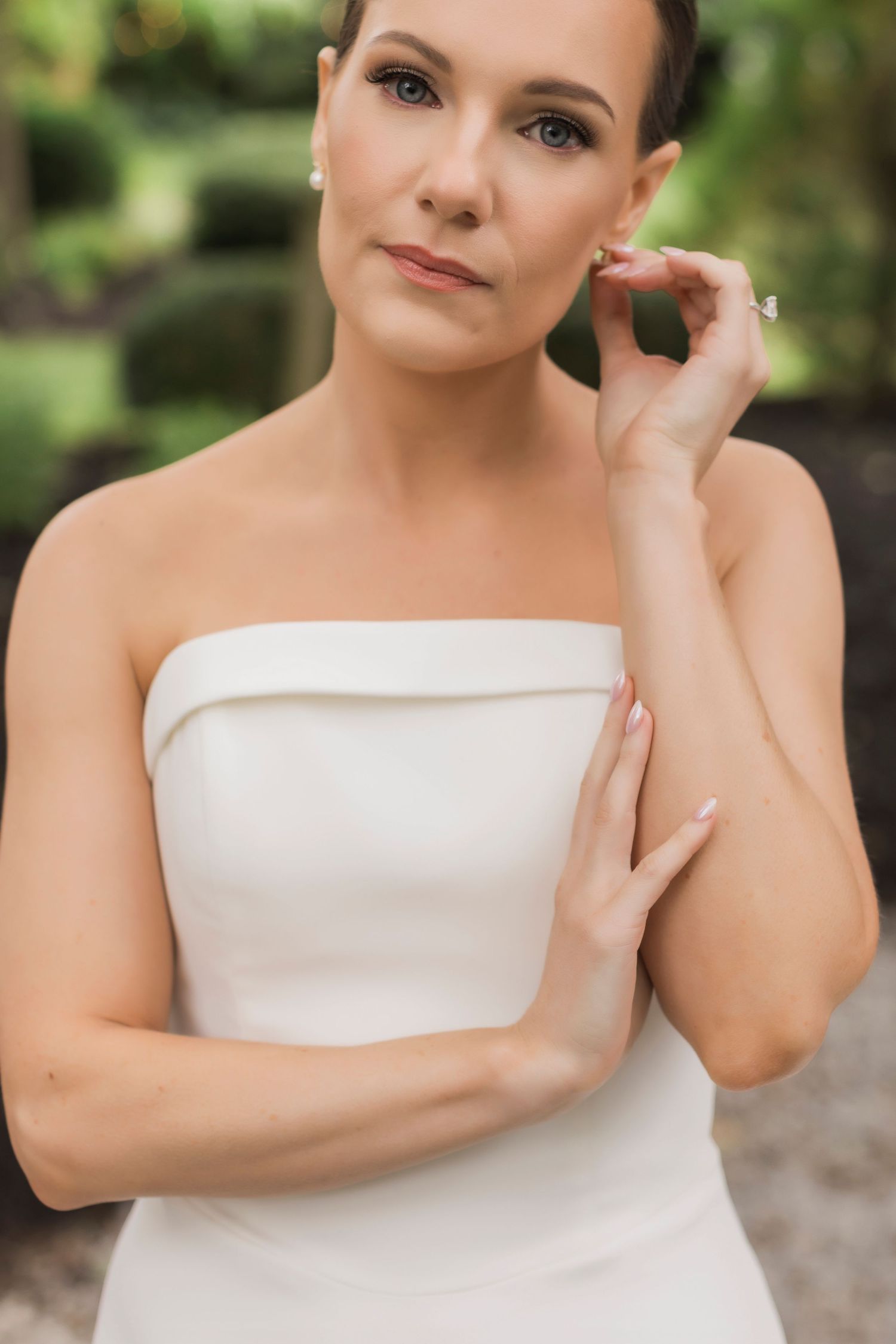 Graceful bridal portrait showcasing a modern strapless white gown against lush garden backdrop.