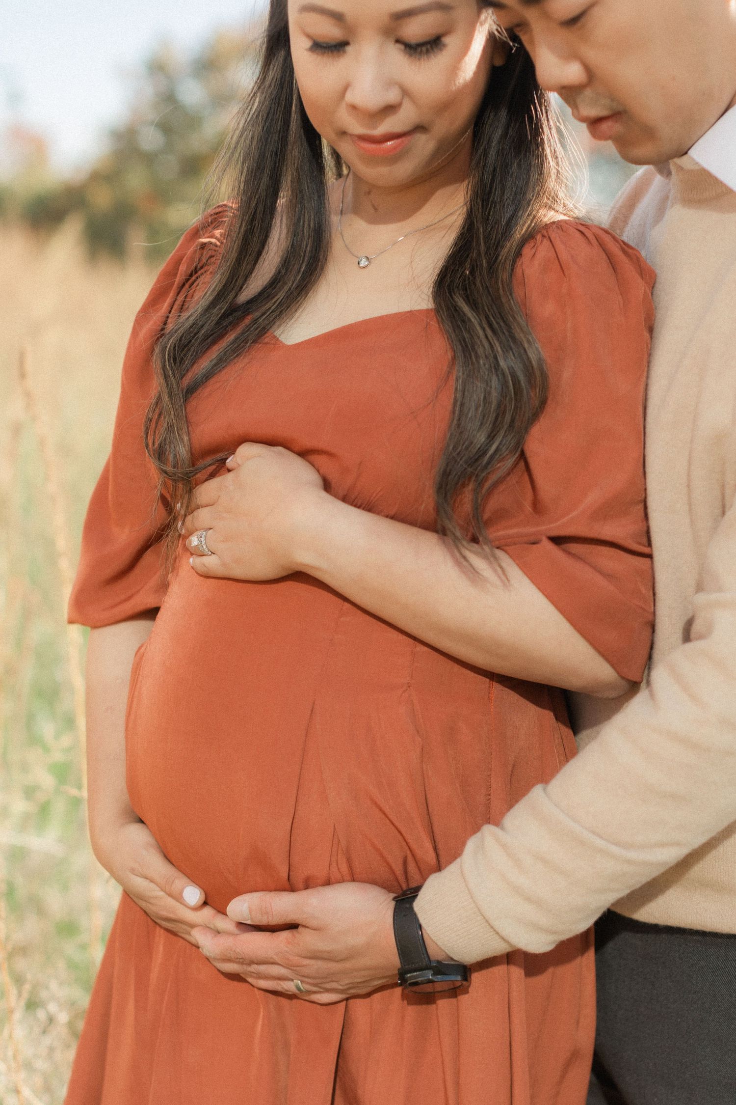 Close-up of expectant parents sharing an intimate moment in a golden field.