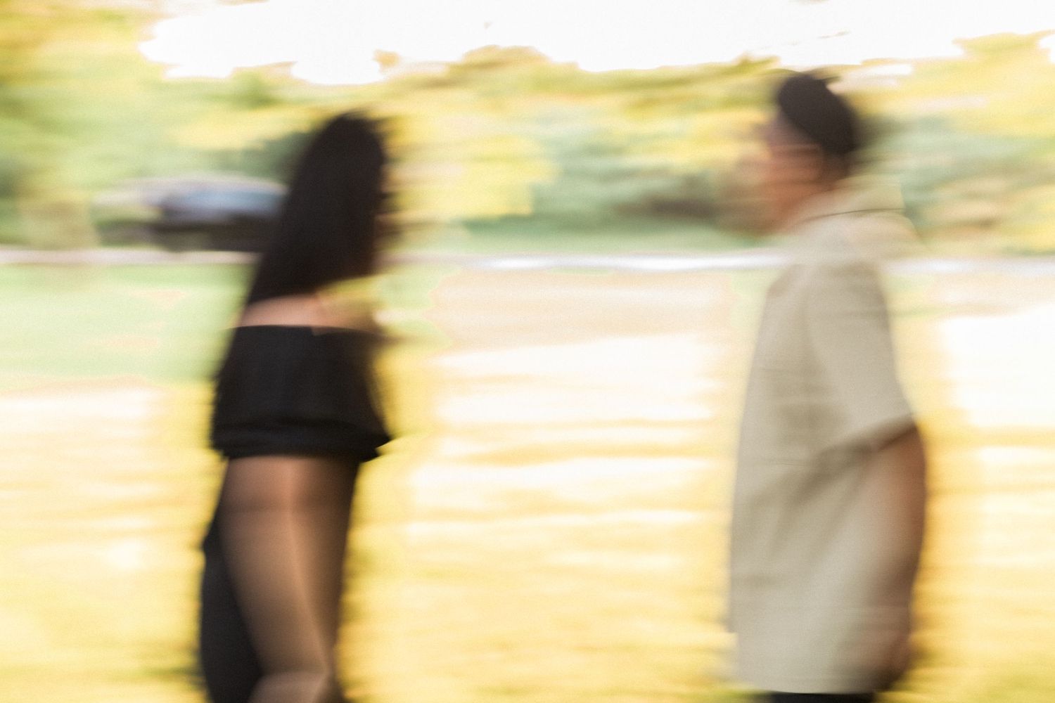 Abstract blurred silhouettes of two people standing in golden sunset light.