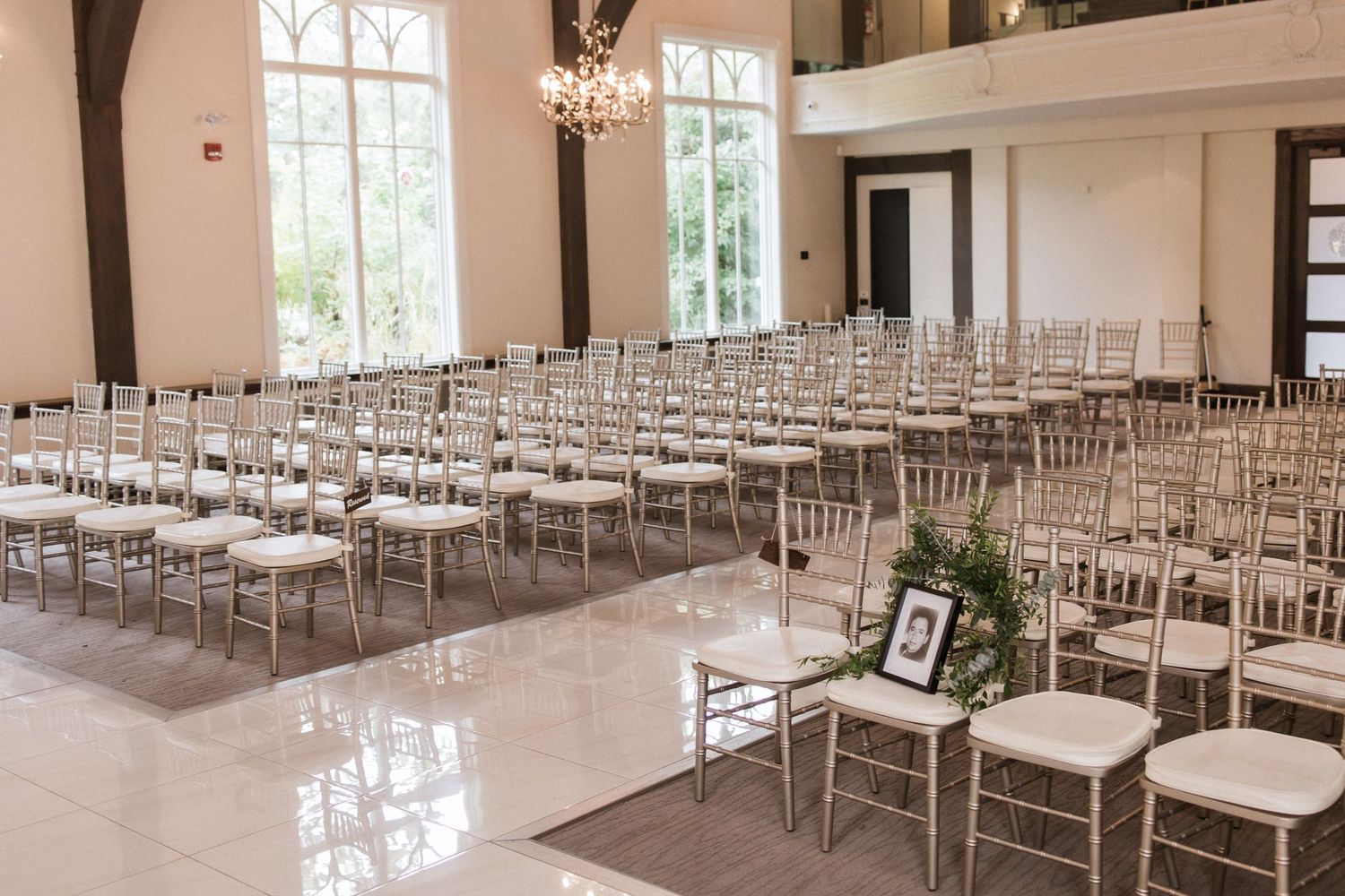 Bright chapel interior with polished floors and rows of silver Chiavari chairs for wedding ceremony.