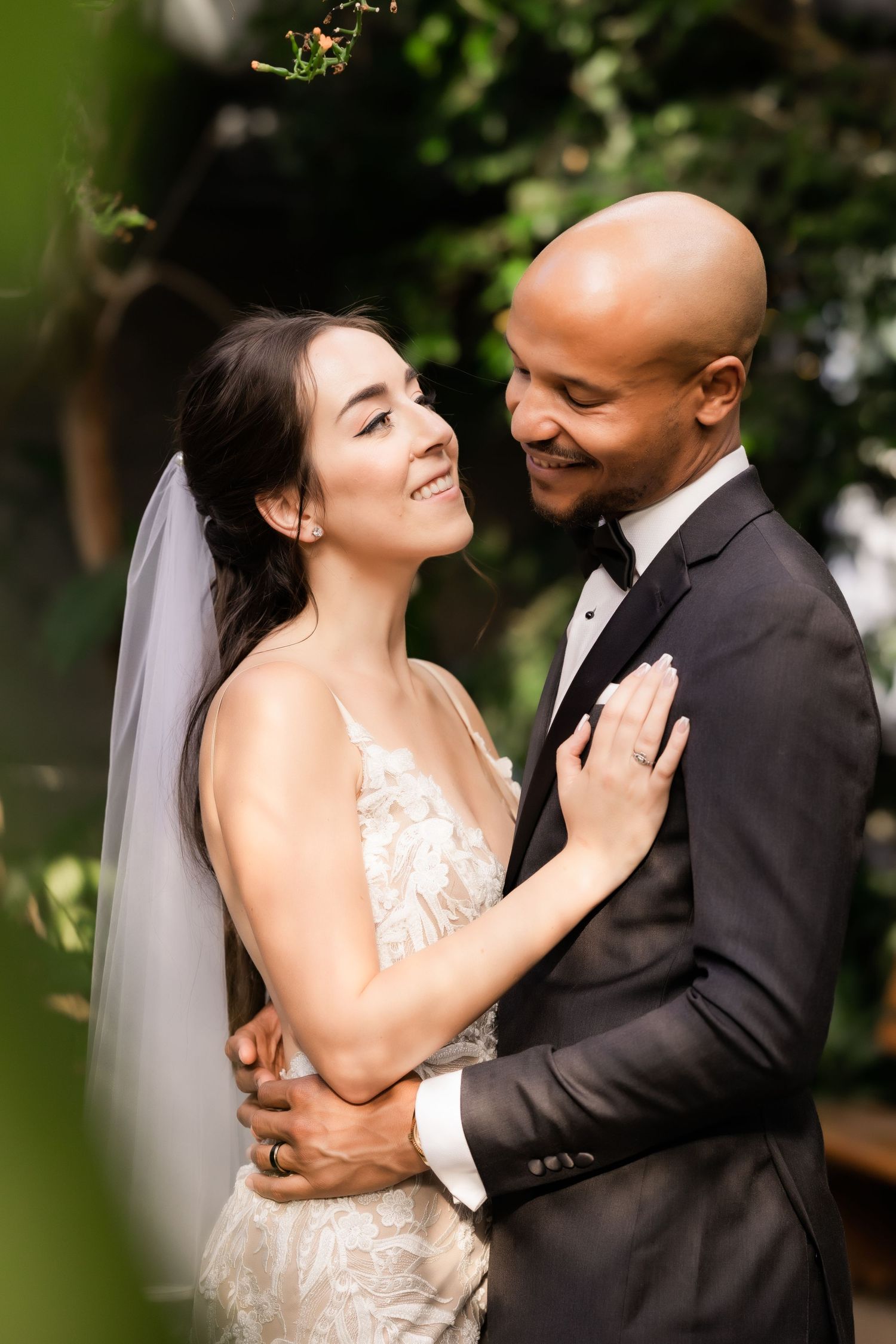 Candid wedding moment showing genuine laughter and joy between newlyweds in a garden setting.